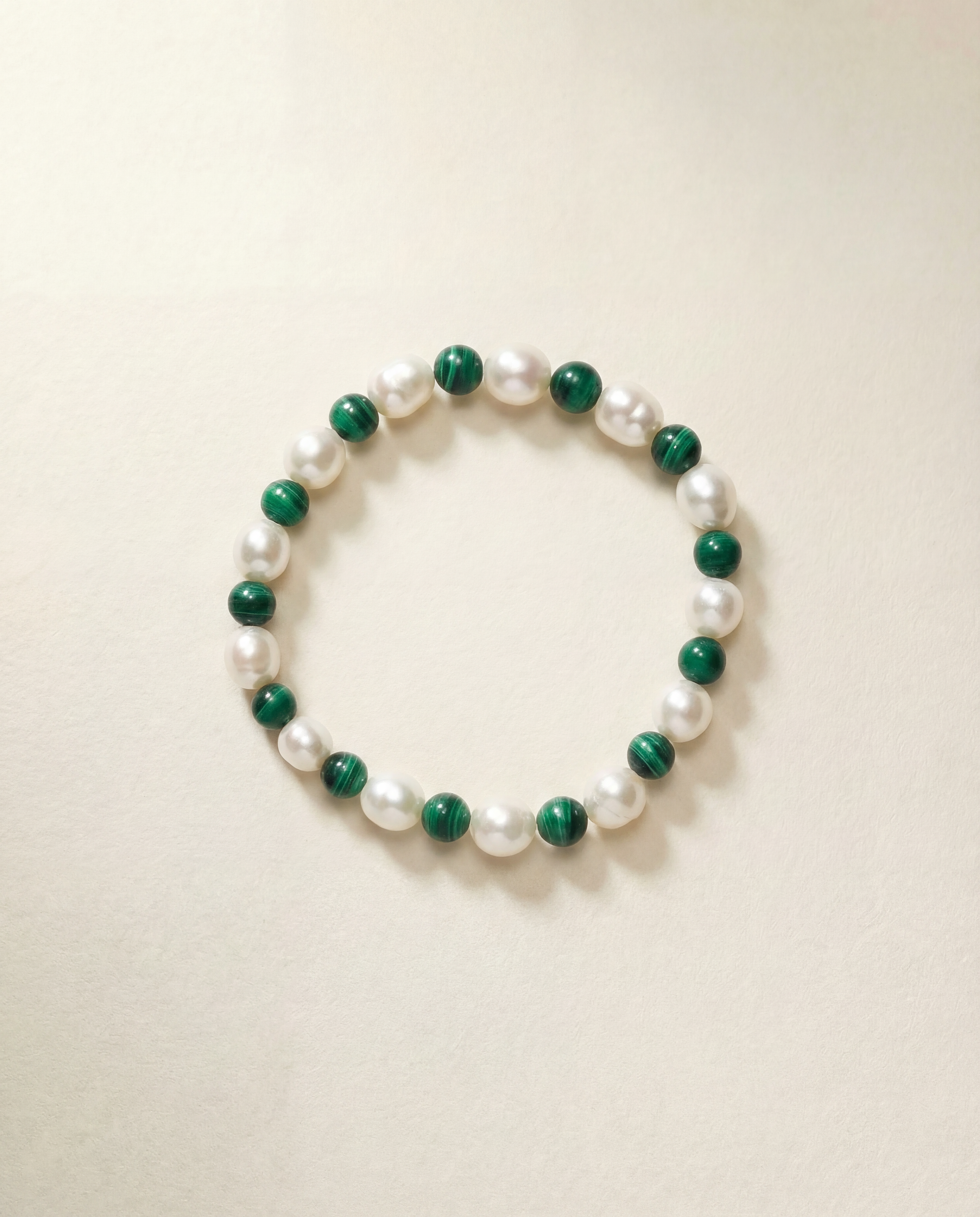Bracelet with green and white beads on a beige background