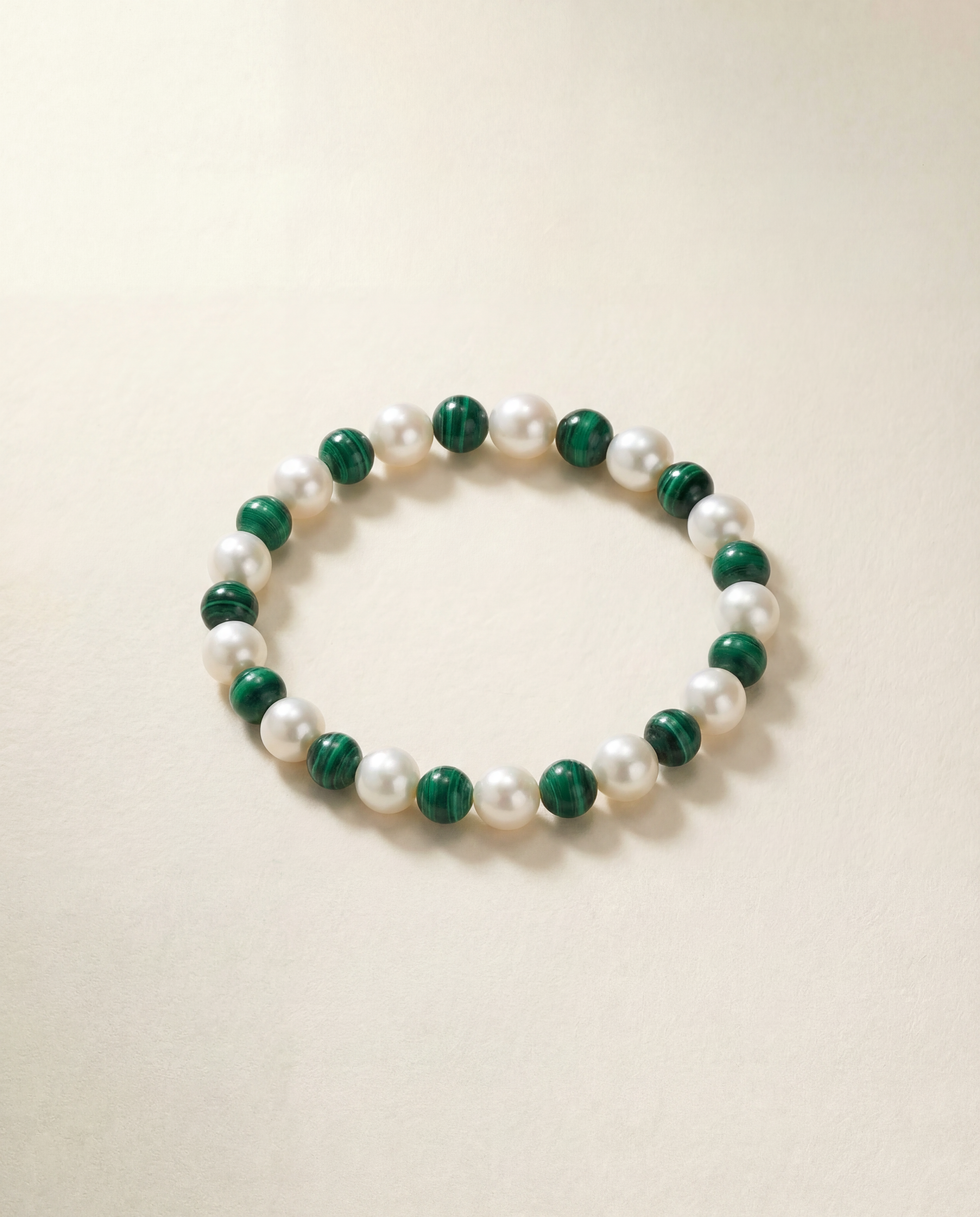 Beaded bracelet with green and white beads on a beige background
