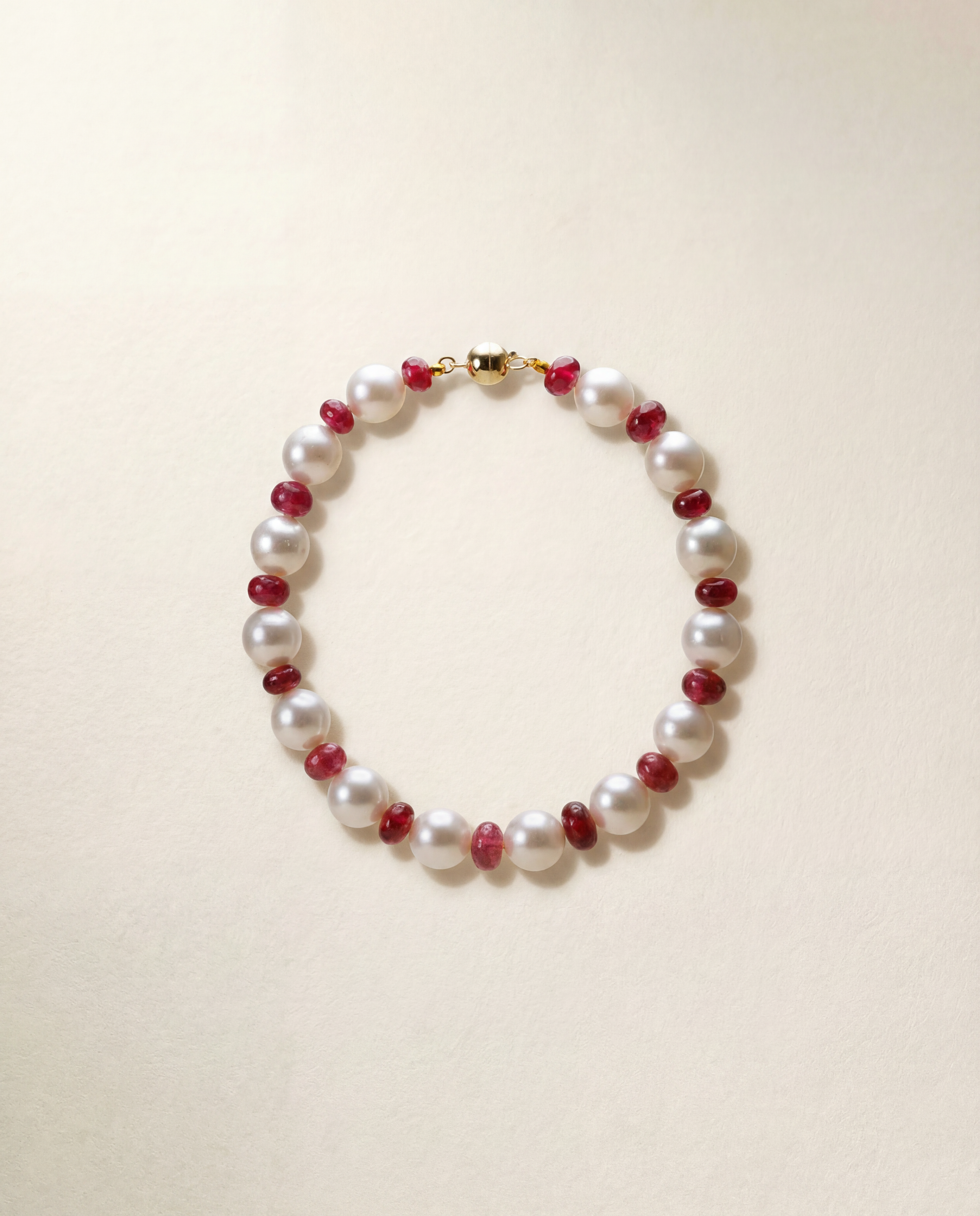 South Sea Pearl and red spinel bracelet with 9k yellow gold clasp on a white background