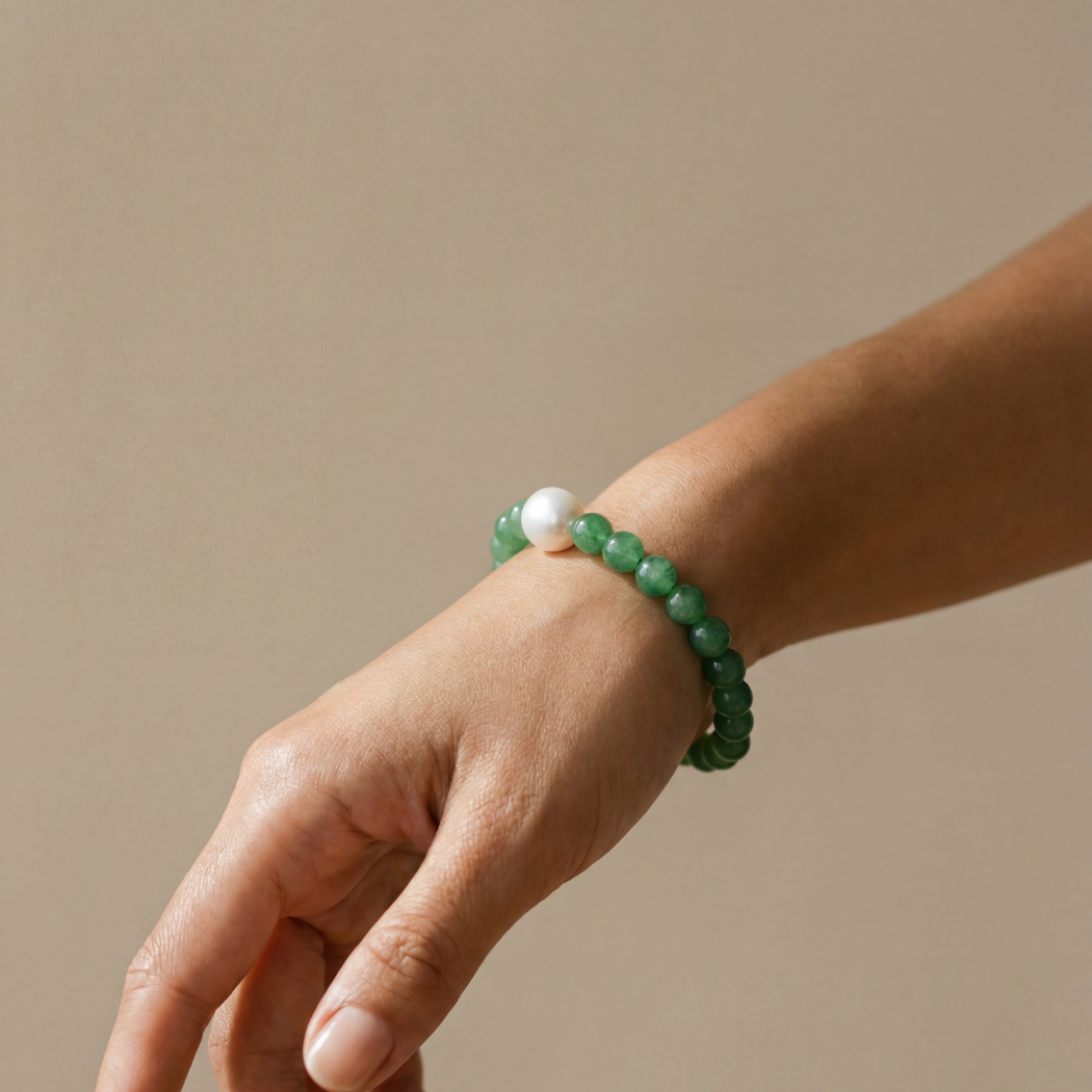 Green beaded bracelet on a wrist against a beige background