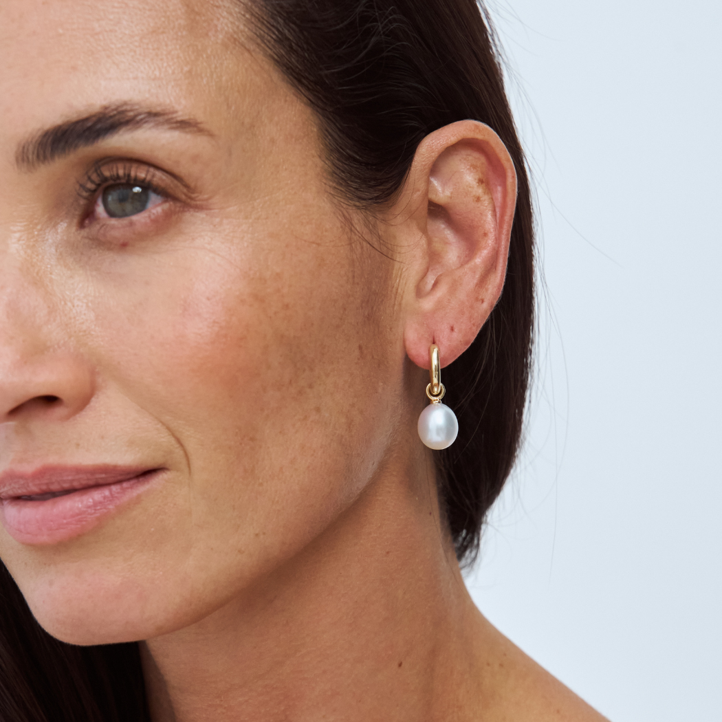 Close-up of a model wearing a South Sea pearl drop earring on a 9k solid gold hoop.