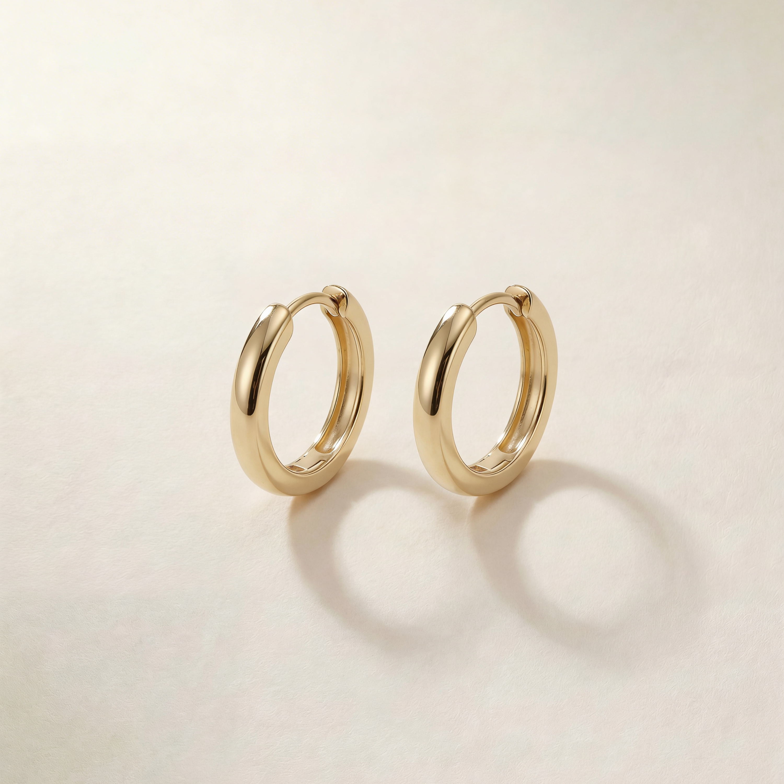 Gold hoop earrings on a light beige background