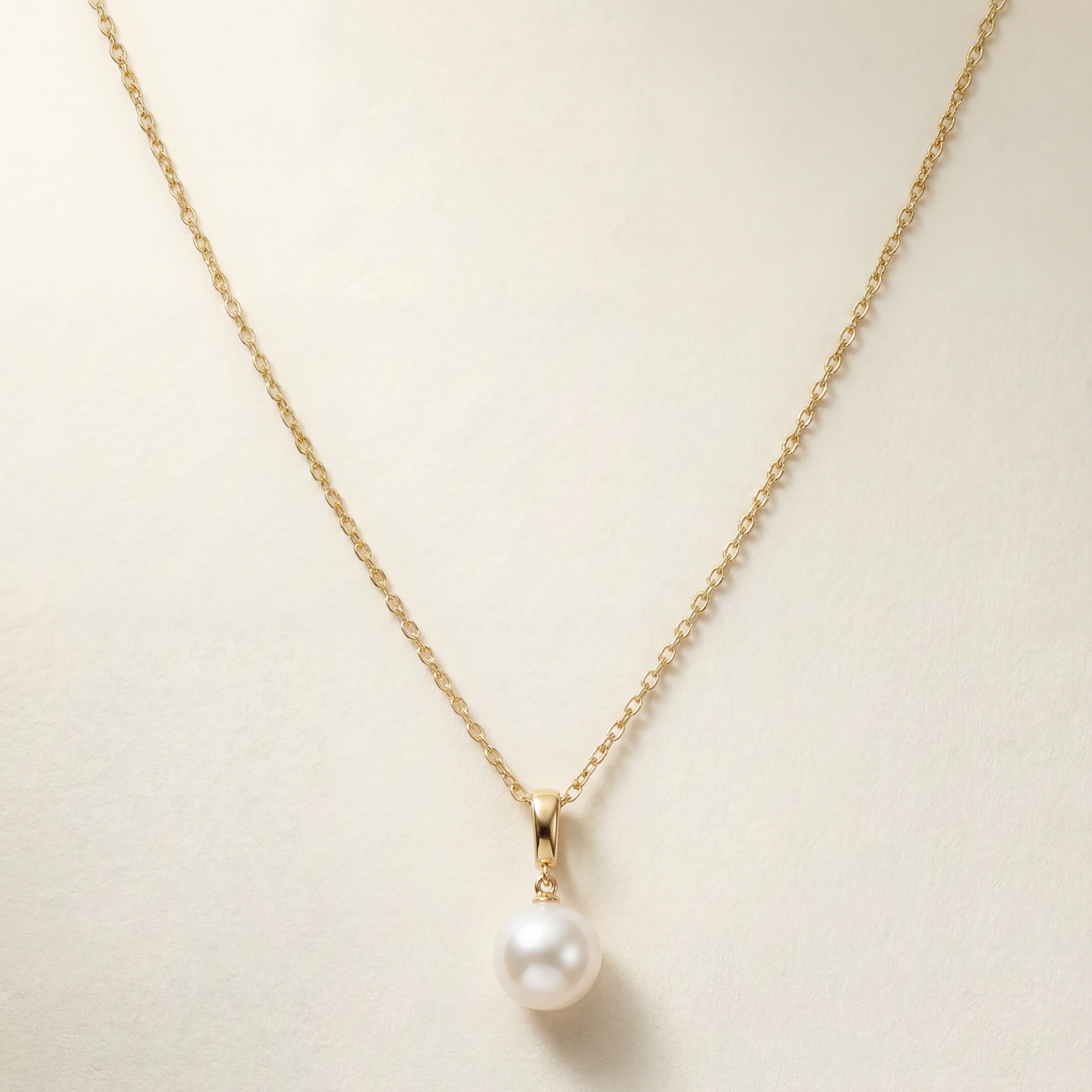 Pearl necklace on a gold chain against a beige background