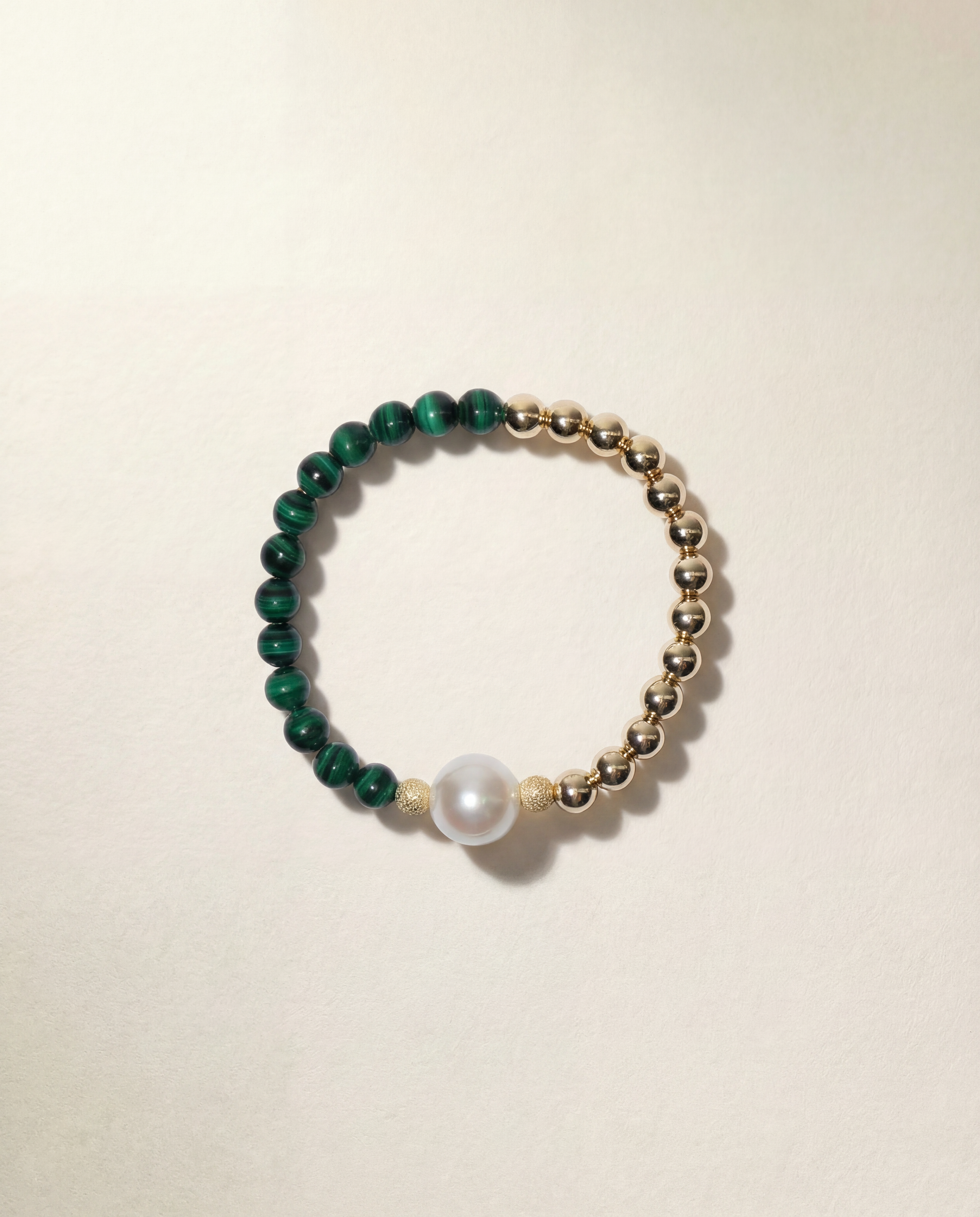 Bracelet with green beads and a pearl on a beige background