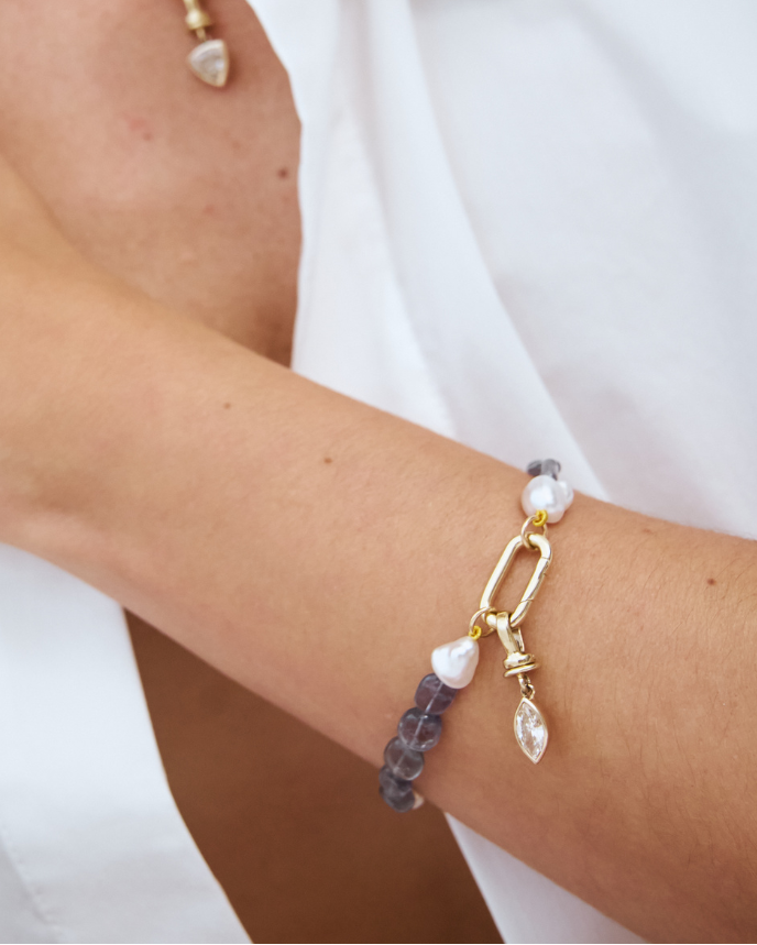 Close-up of a model wearing an iolite and keshi bracelet with a champagne Marquise diamond