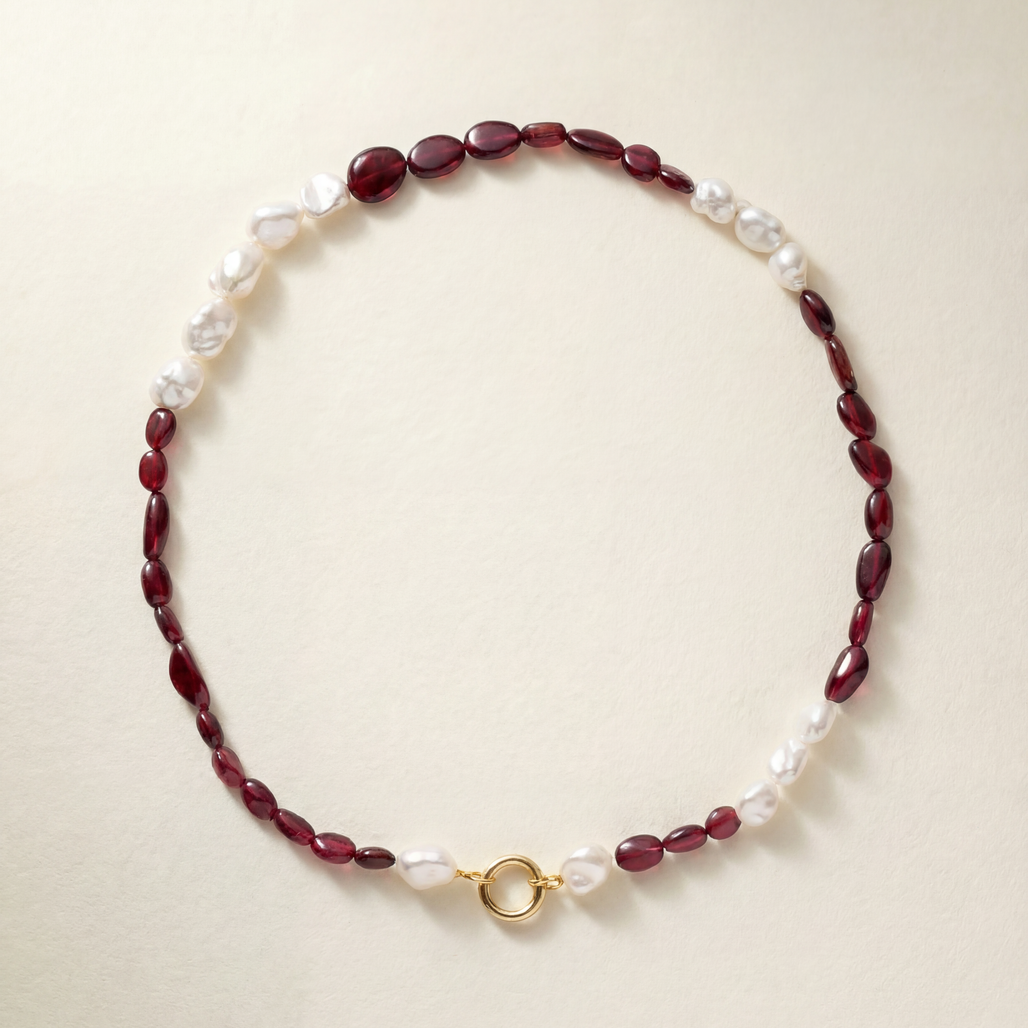 Beaded necklace with red beads and pearls on a beige background