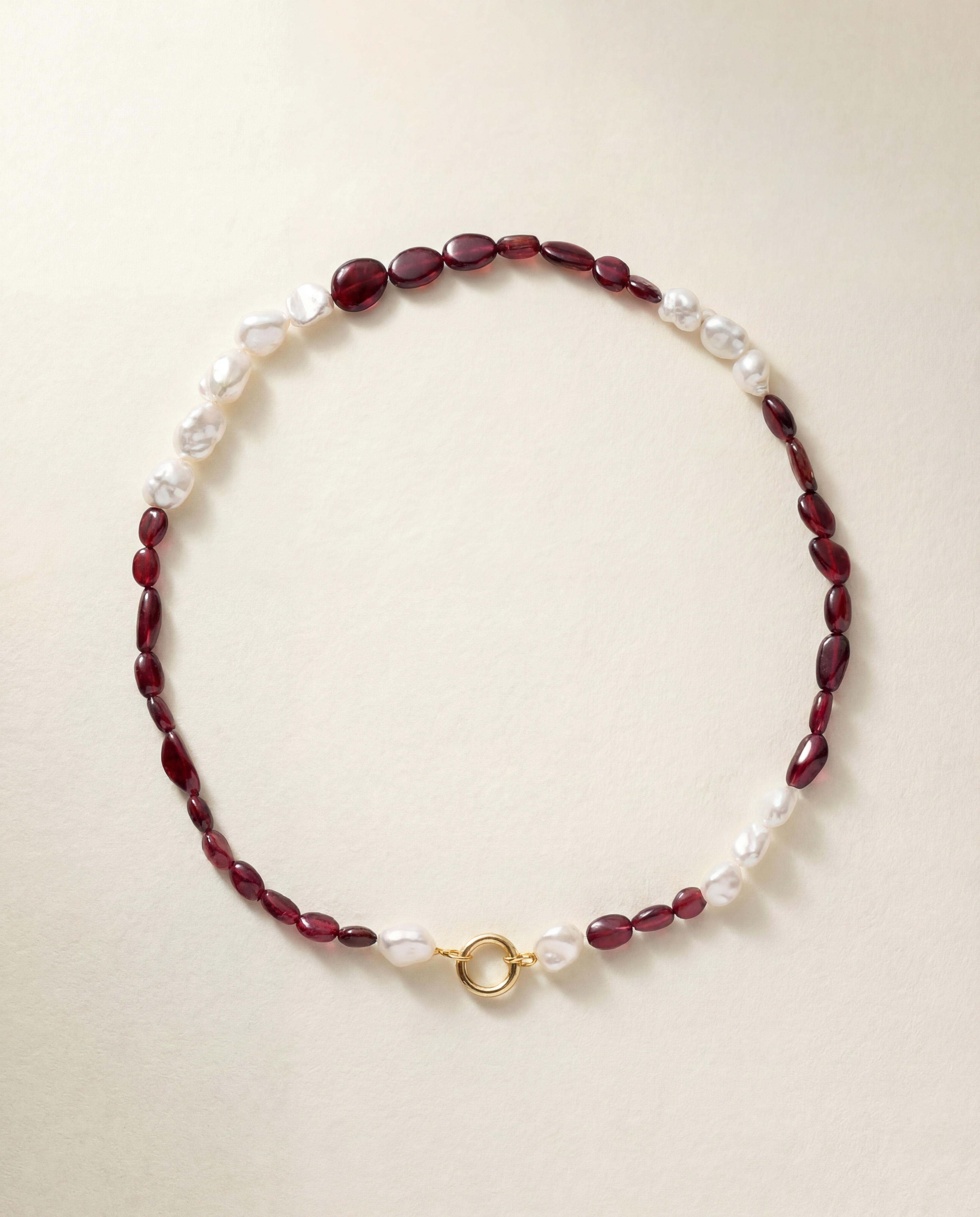 Beaded necklace with red beads and pearls on a beige background