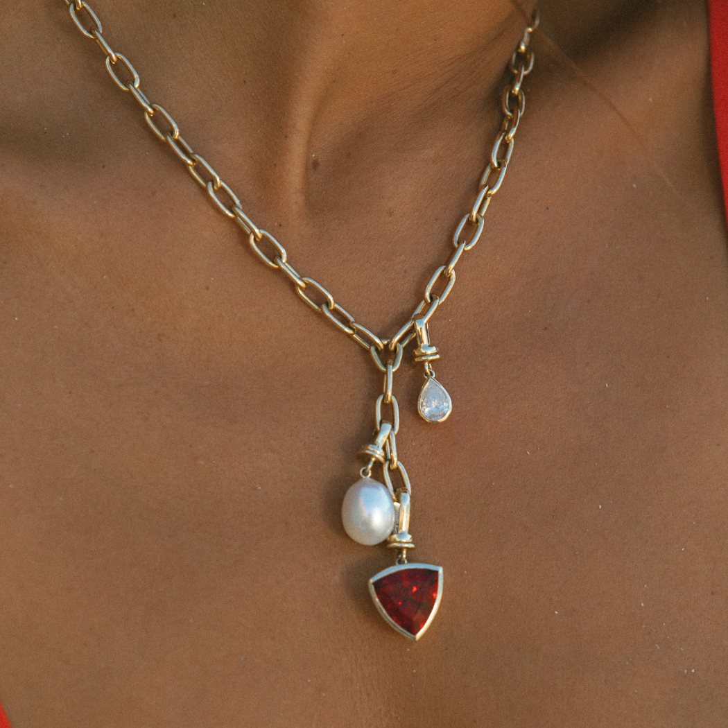 Close-up of 9k solid gold necklace with various gemstones and pearl charms.