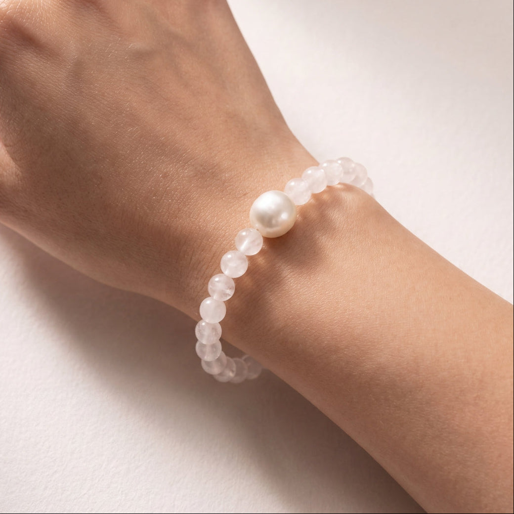 A close-up of a person's wrist wearing a beaded rose quartz bracelet featuring south sea pearls.