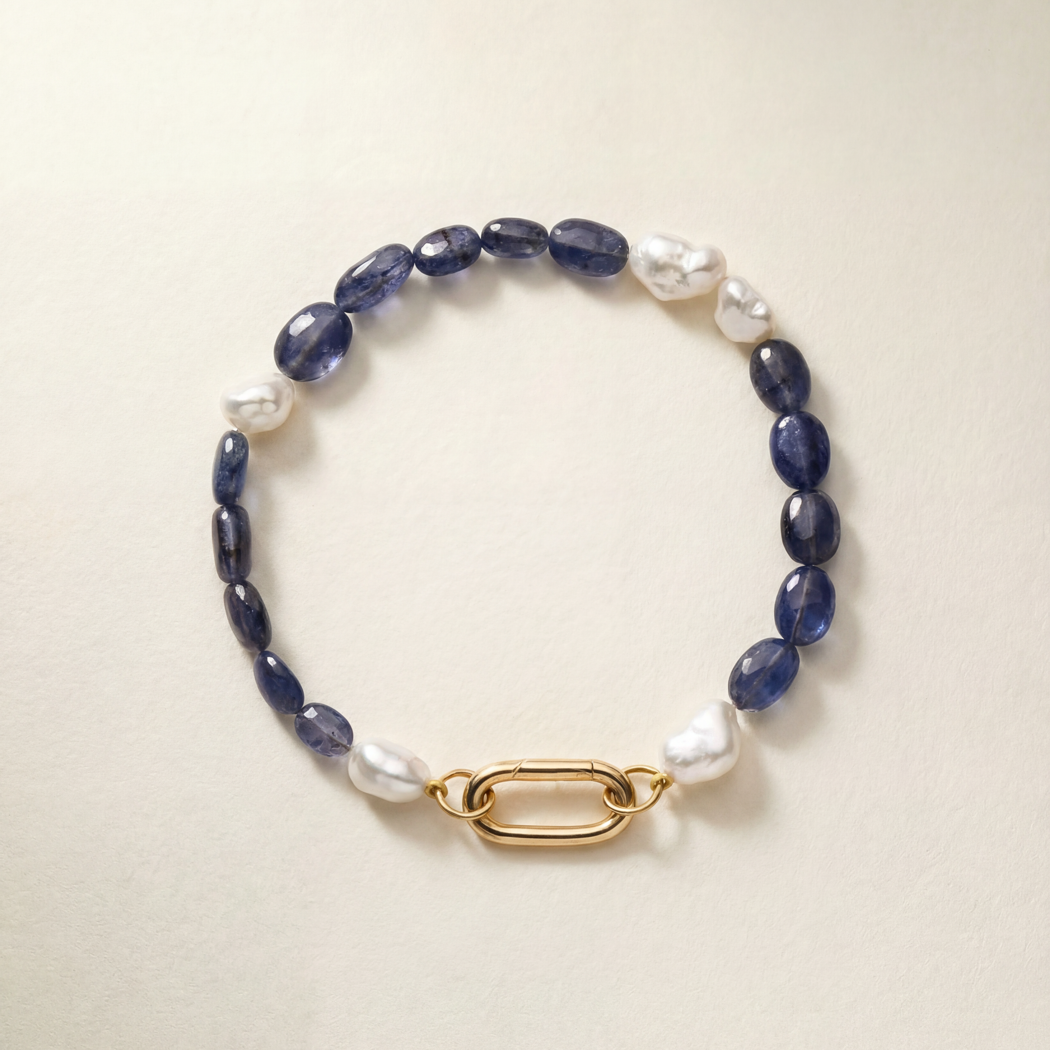 Bracelet with pearls and blue beads and a gold clasp on a beige background