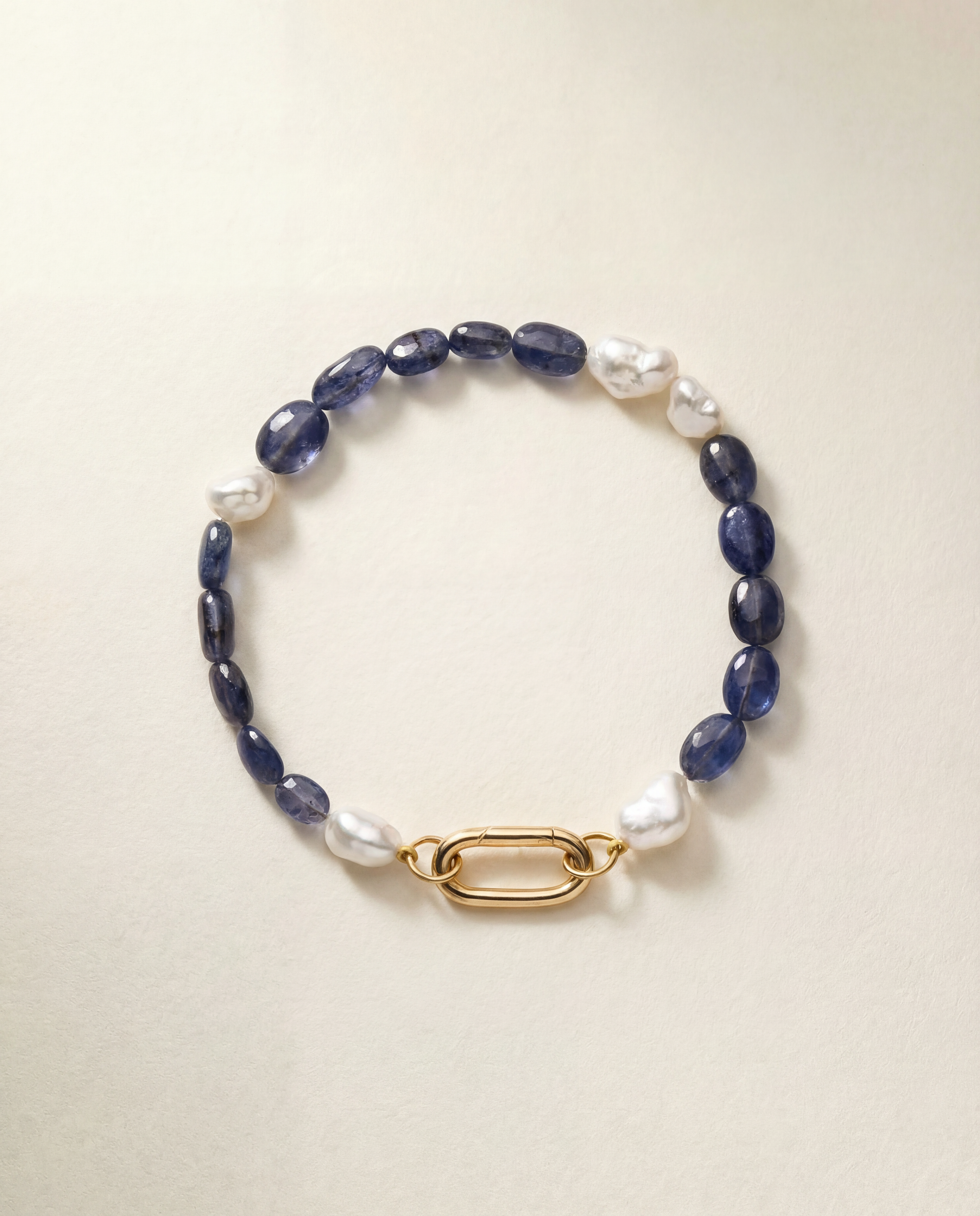 Bracelet with pearls and blue beads and a gold clasp on a beige background