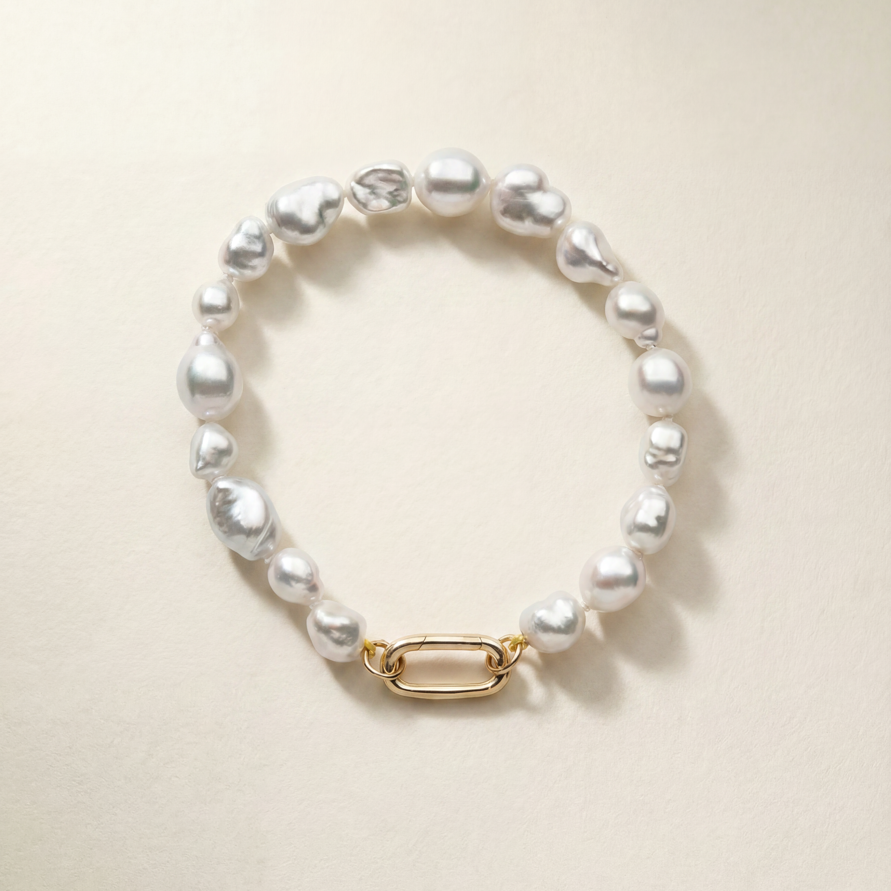 Pearl bracelet with a gold clasp on a beige background