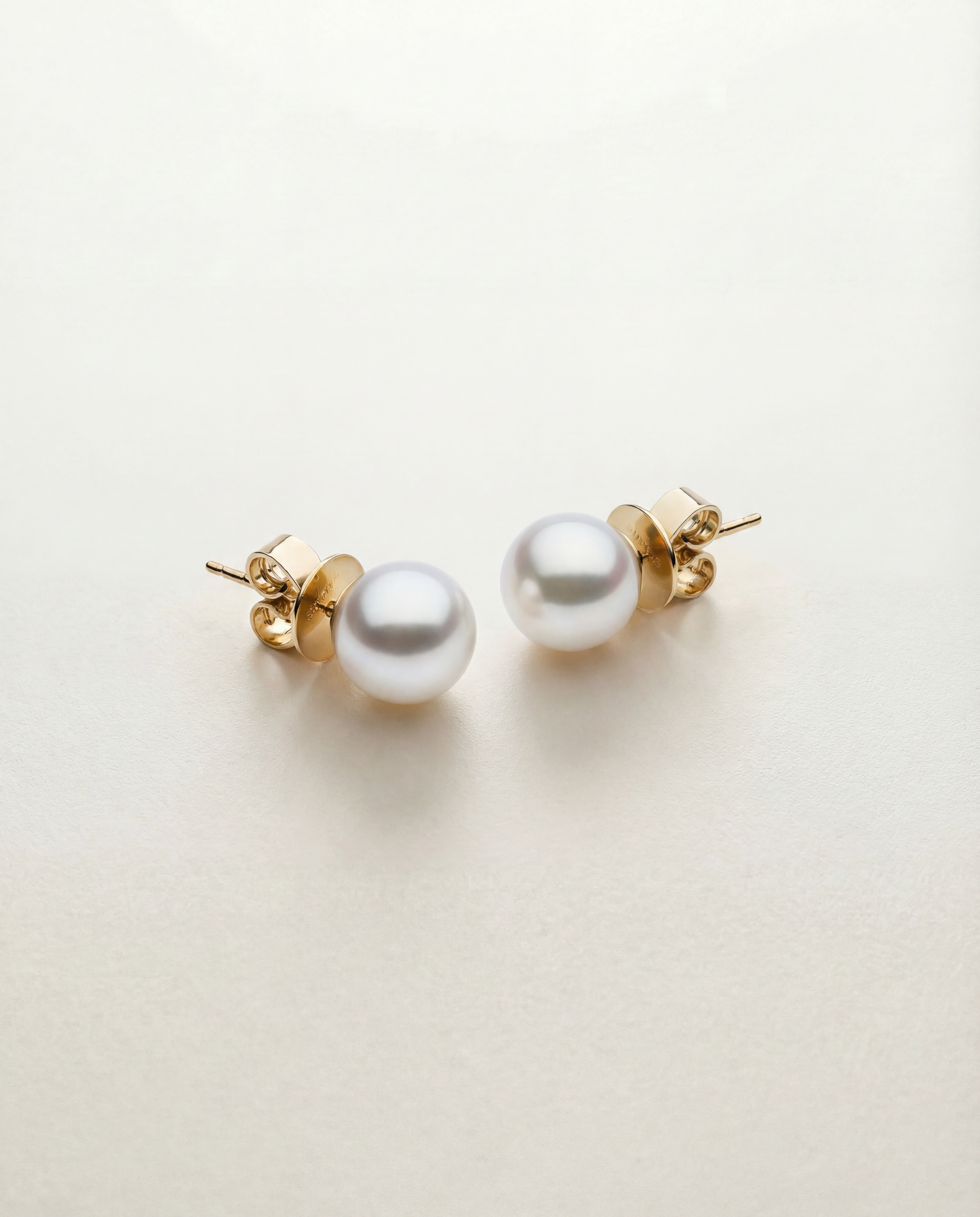 Pearl earrings with gold posts on a light beige background