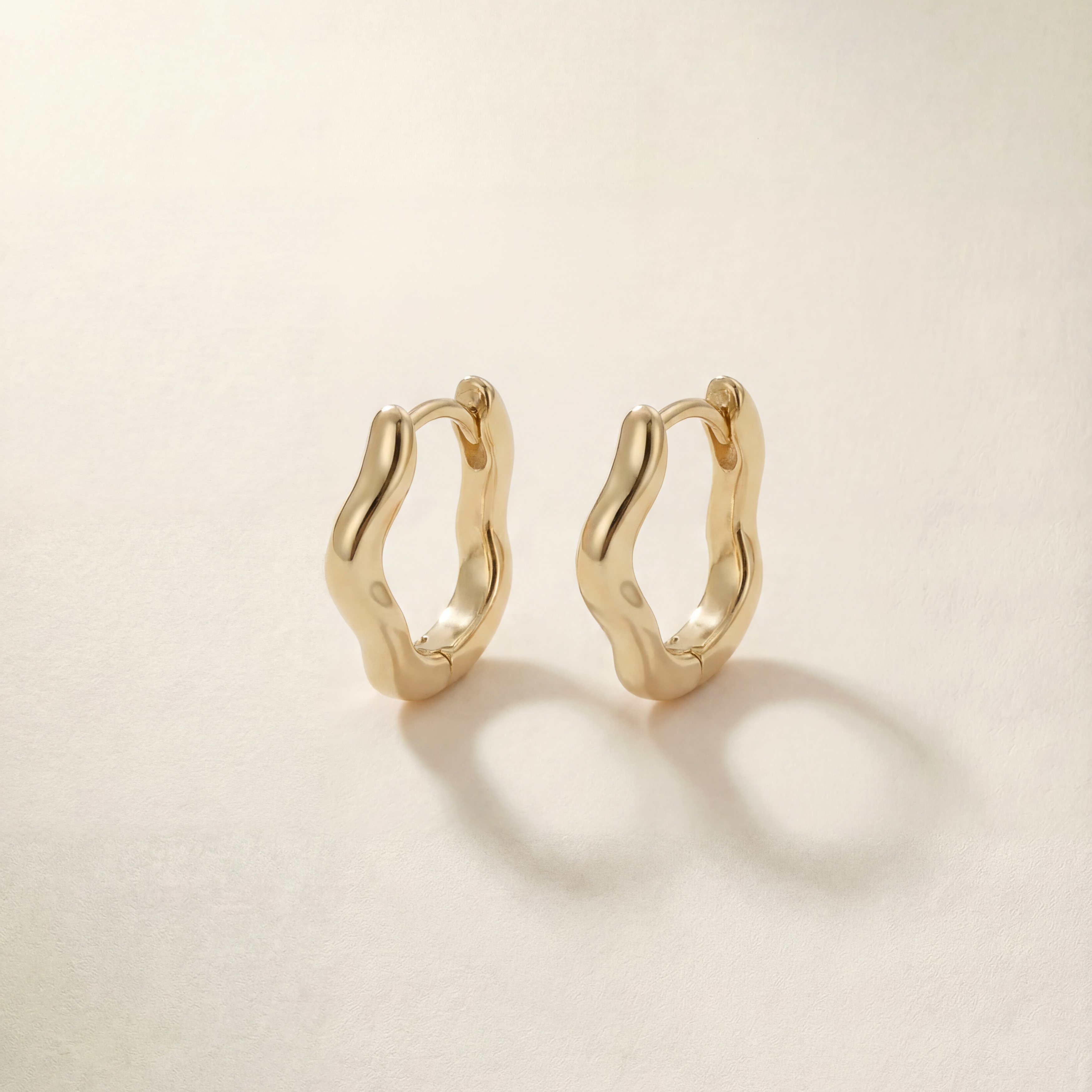 Gold hoop earrings on a light beige background