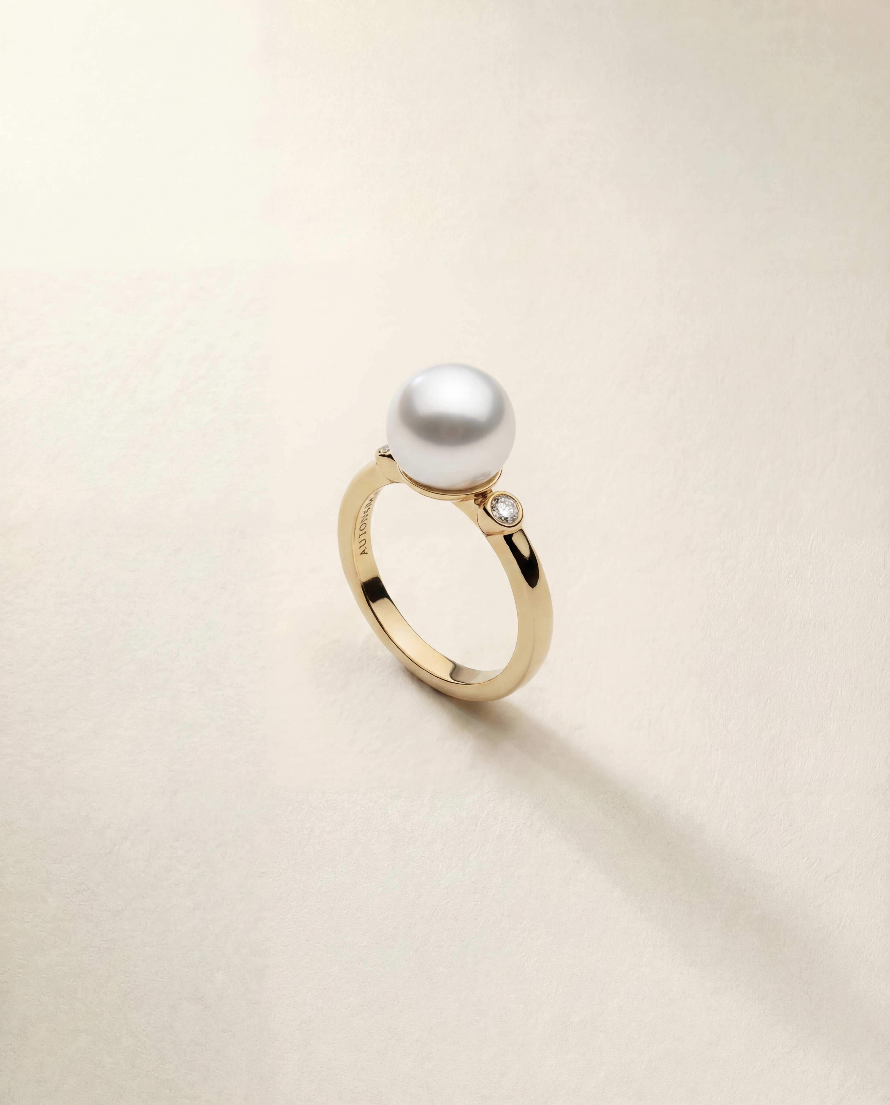 Gold ring with a pearl and small diamond on a beige background