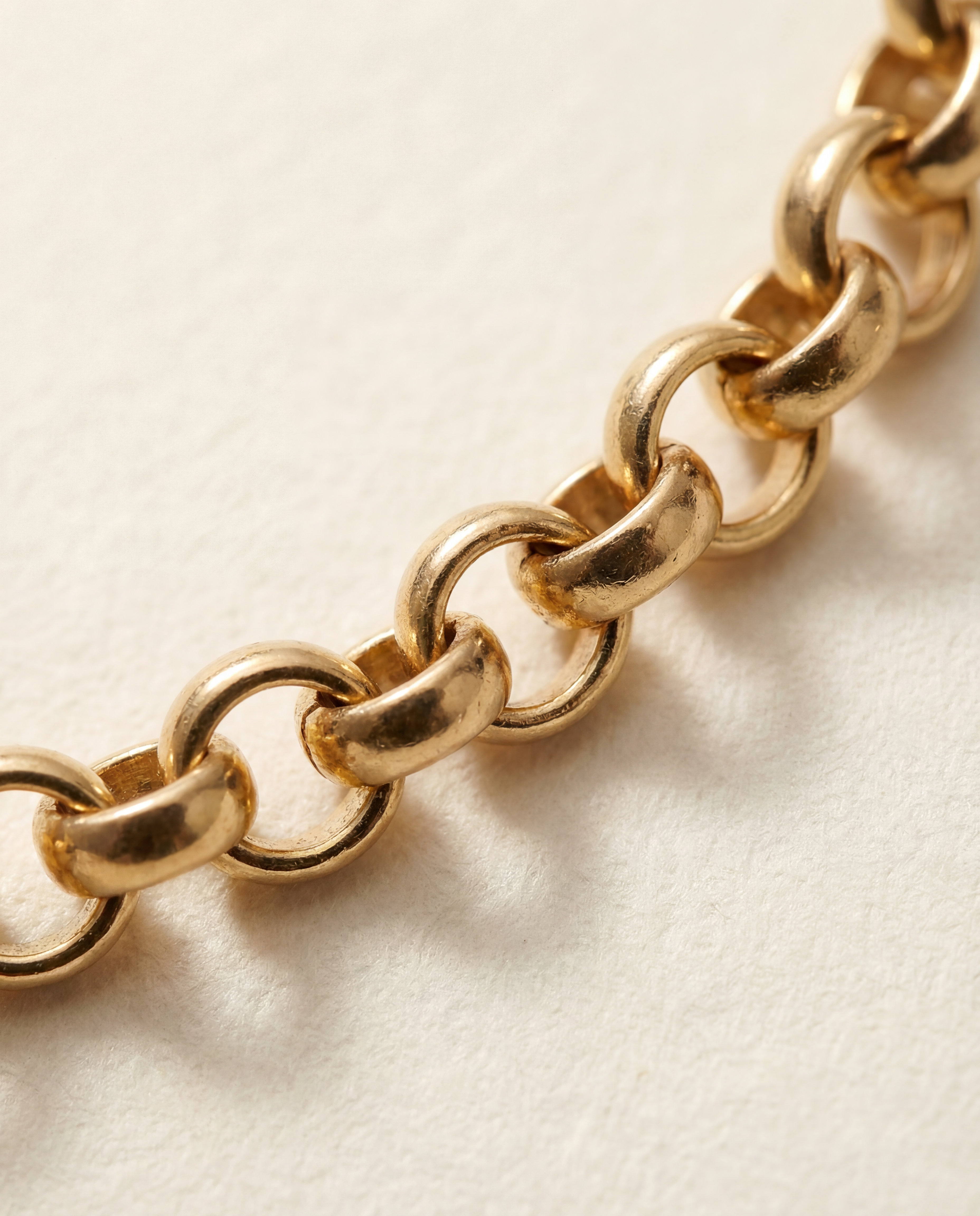 Close-up of a gold chain on a light beige background