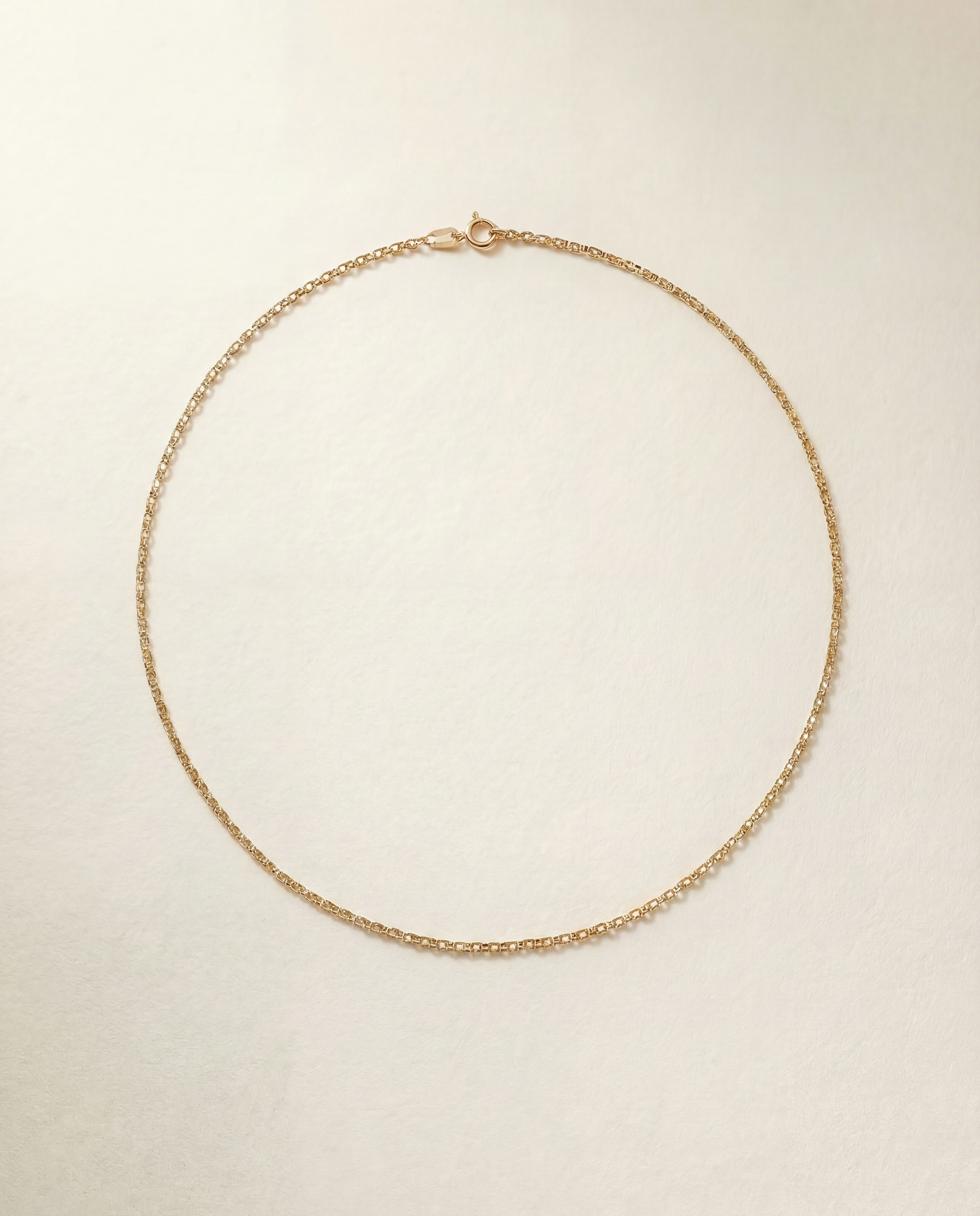 Gold necklace on a light beige background
