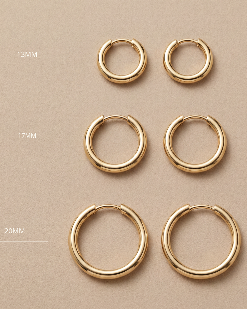 Set of gold hoop earrings in various sizes on a beige background