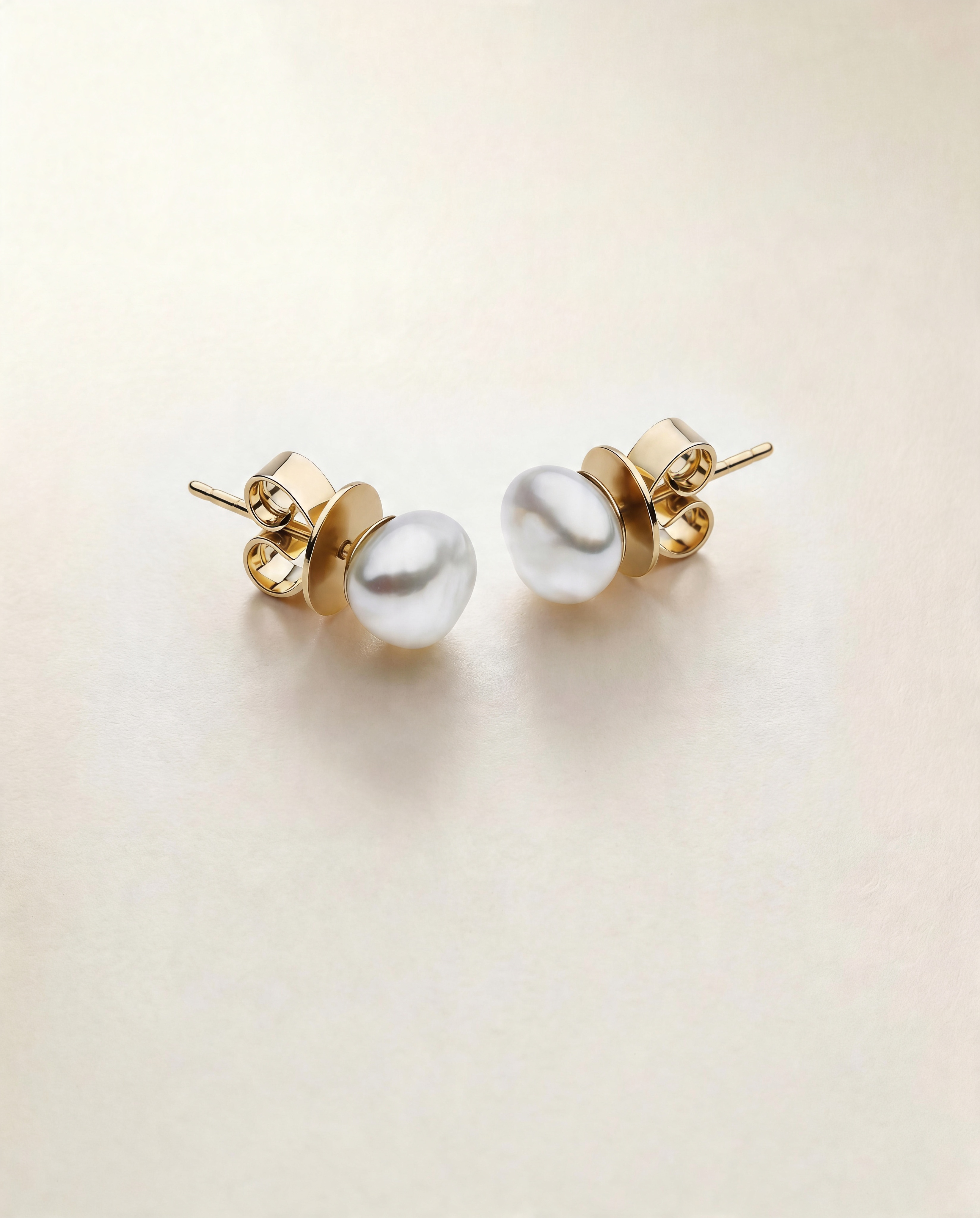 Pair of pearl earrings with gold settings on a light beige background