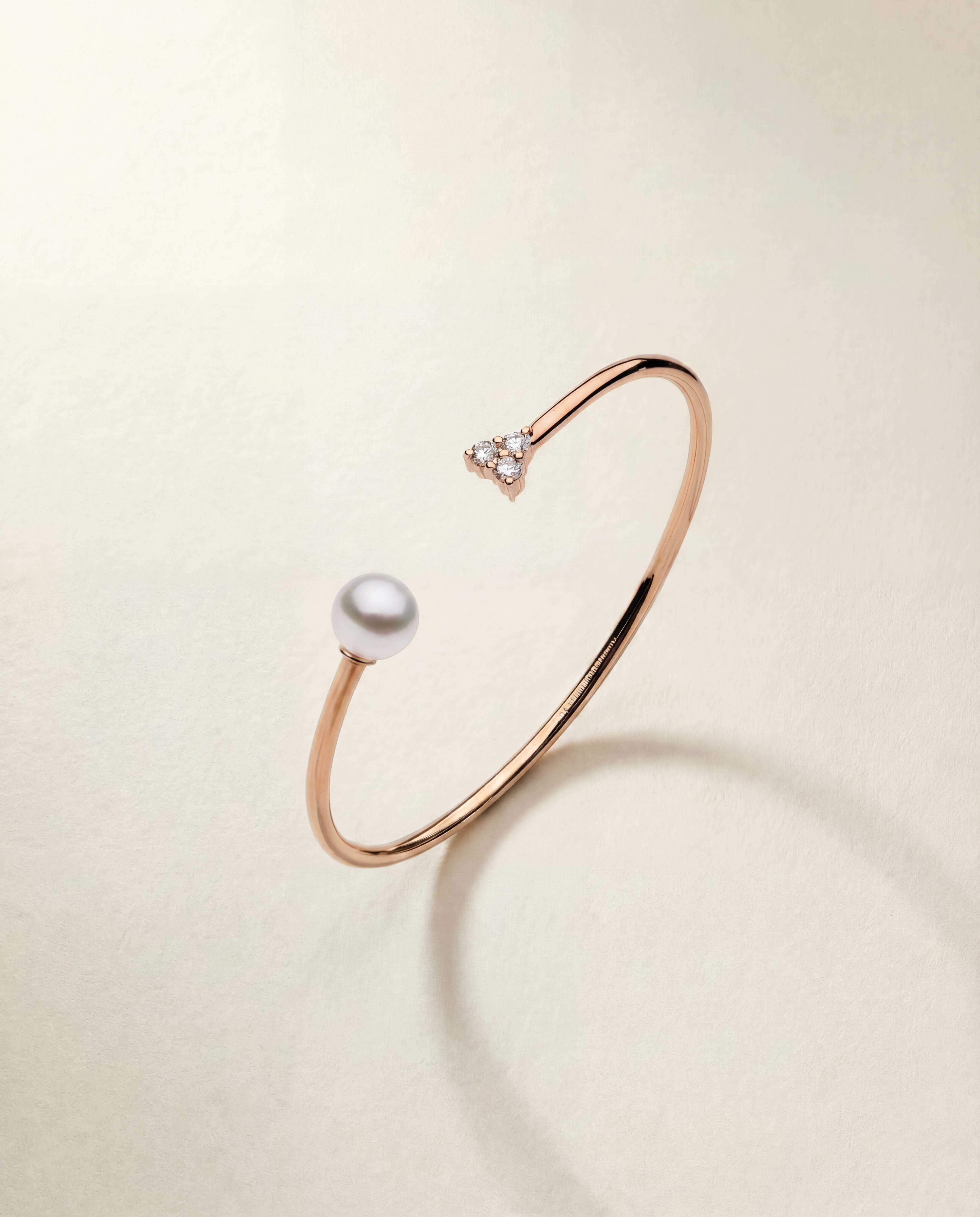 Rose gold bracelet with a pearl and small sapphires on a beige background