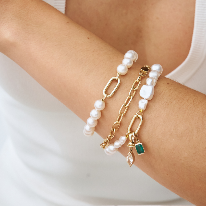 Up close of wrist wearing handmade South Sea Keshi pearl bracelets with 9k solid gold clasp with champagne diamond and emerald charm.