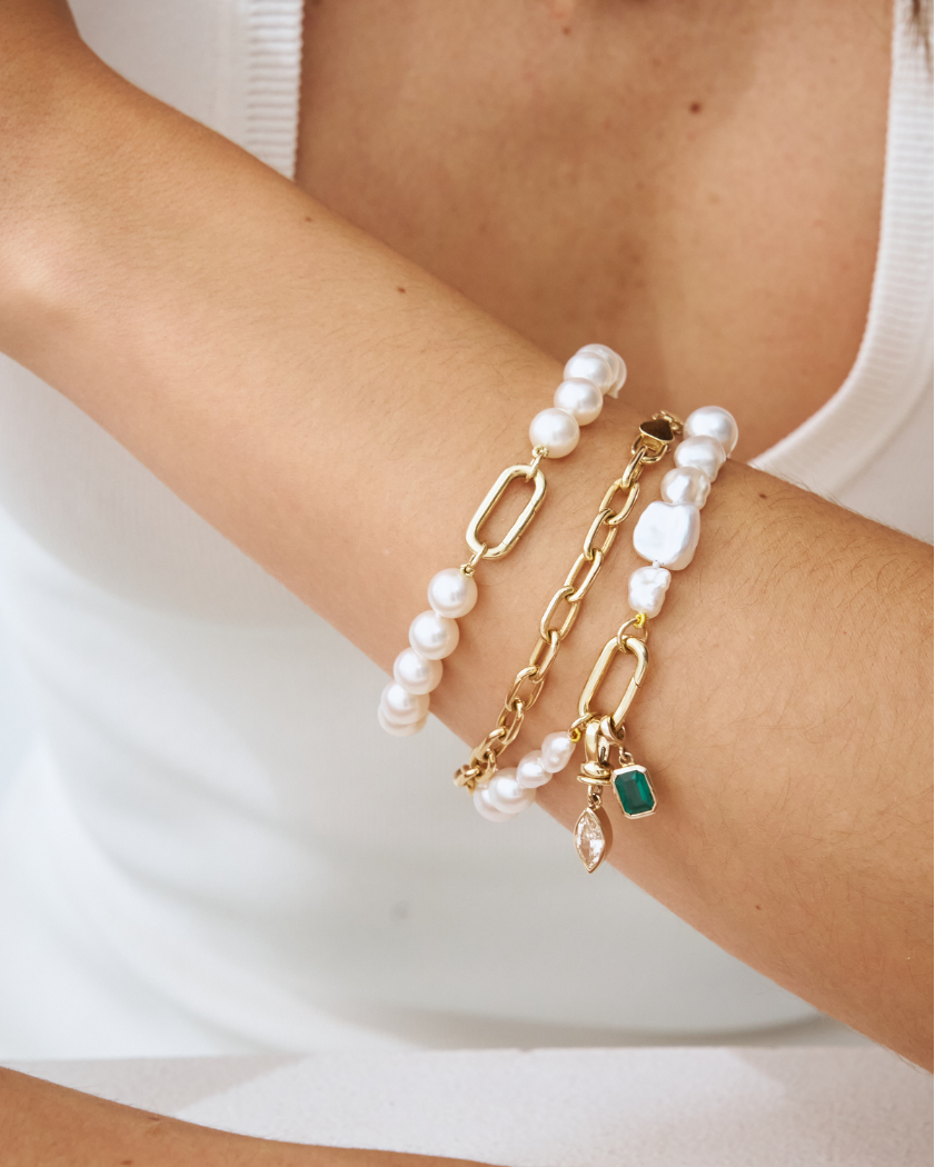 Up close of wrist wearing handmade South Sea Keshi pearl bracelets with 9k solid gold clasp with champagne diamond and emerald charm.