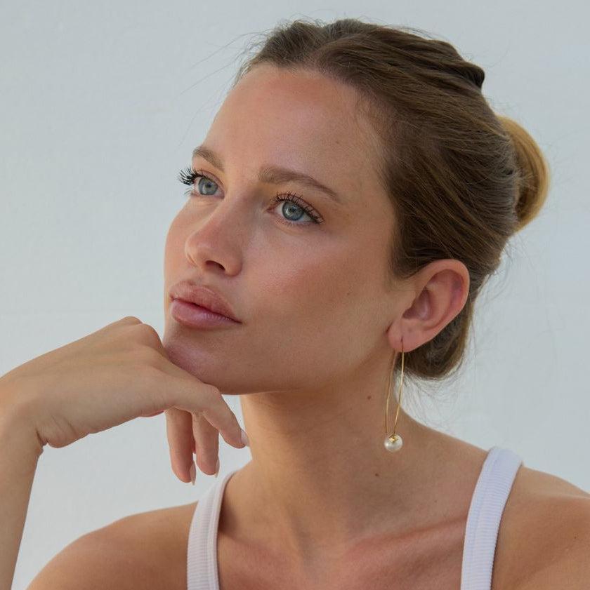 Woman wearing a white tank top against a plain background