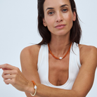 Woman wearing an amber and gold beaded necklace and bracelet on a white background