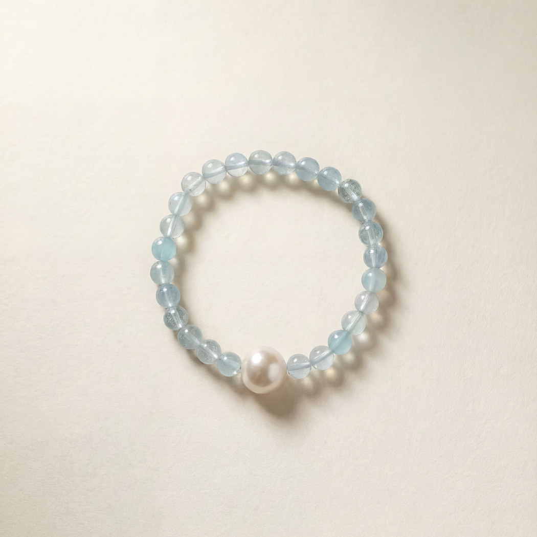 Aquamarine Beaded bracelet with a pearl on a beige background