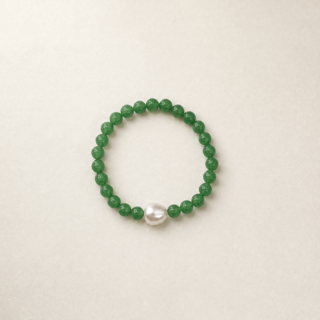 Green beaded bracelet with a pearl on a beige background