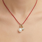 Necklace with a pearl pendant and red string on a person's neck