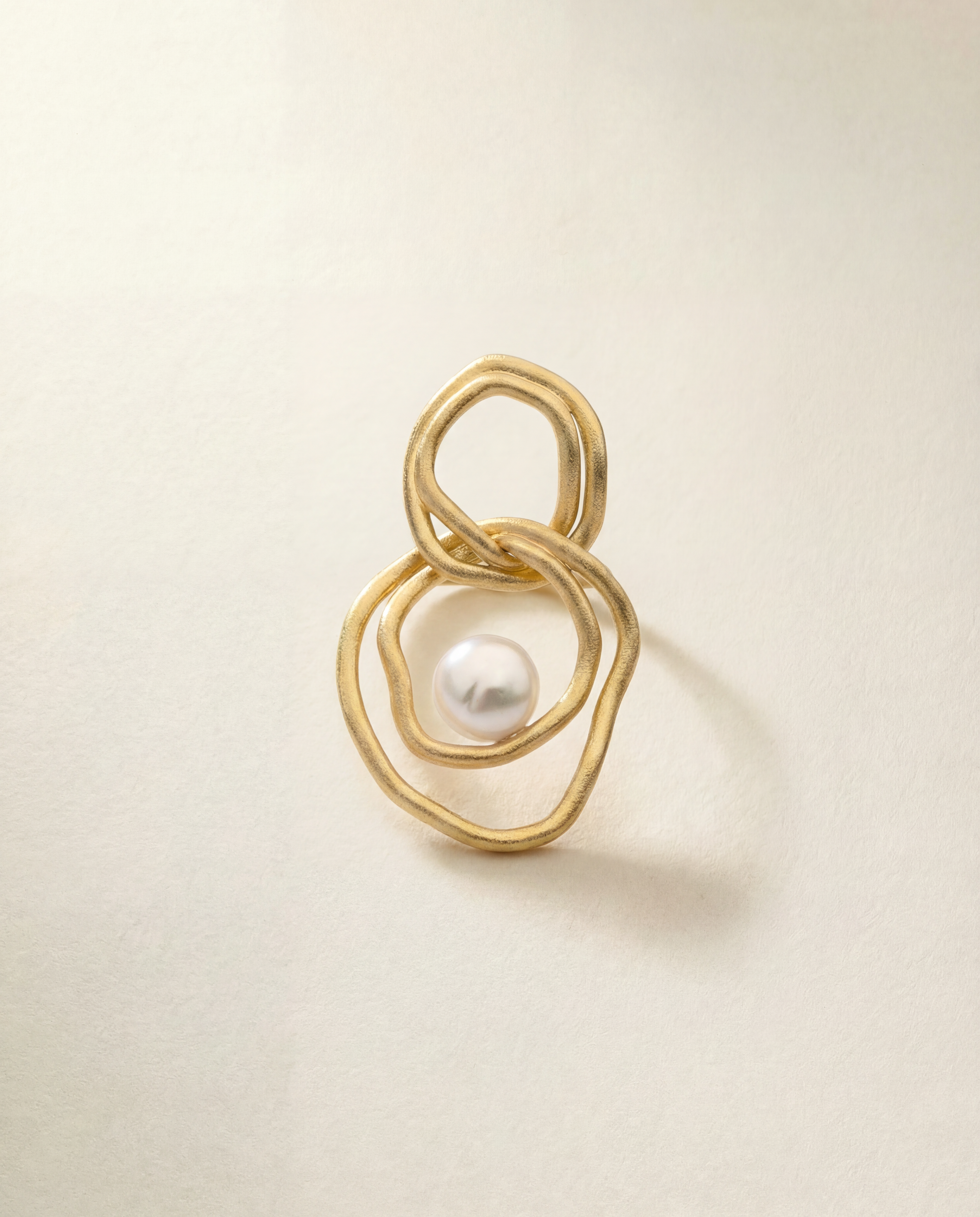 Gold earring with a pearl on a beige background