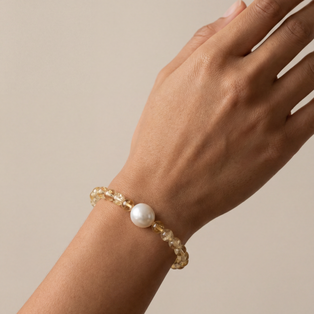 Hand wearing a pearl bracelet on a beige background