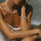 Close-up of a person wearing an 18k gold vermeil Italian-style chain bracelet, paired with a stacked South Sea pearl bracelet and a necklace featuring natural diamond charms. 