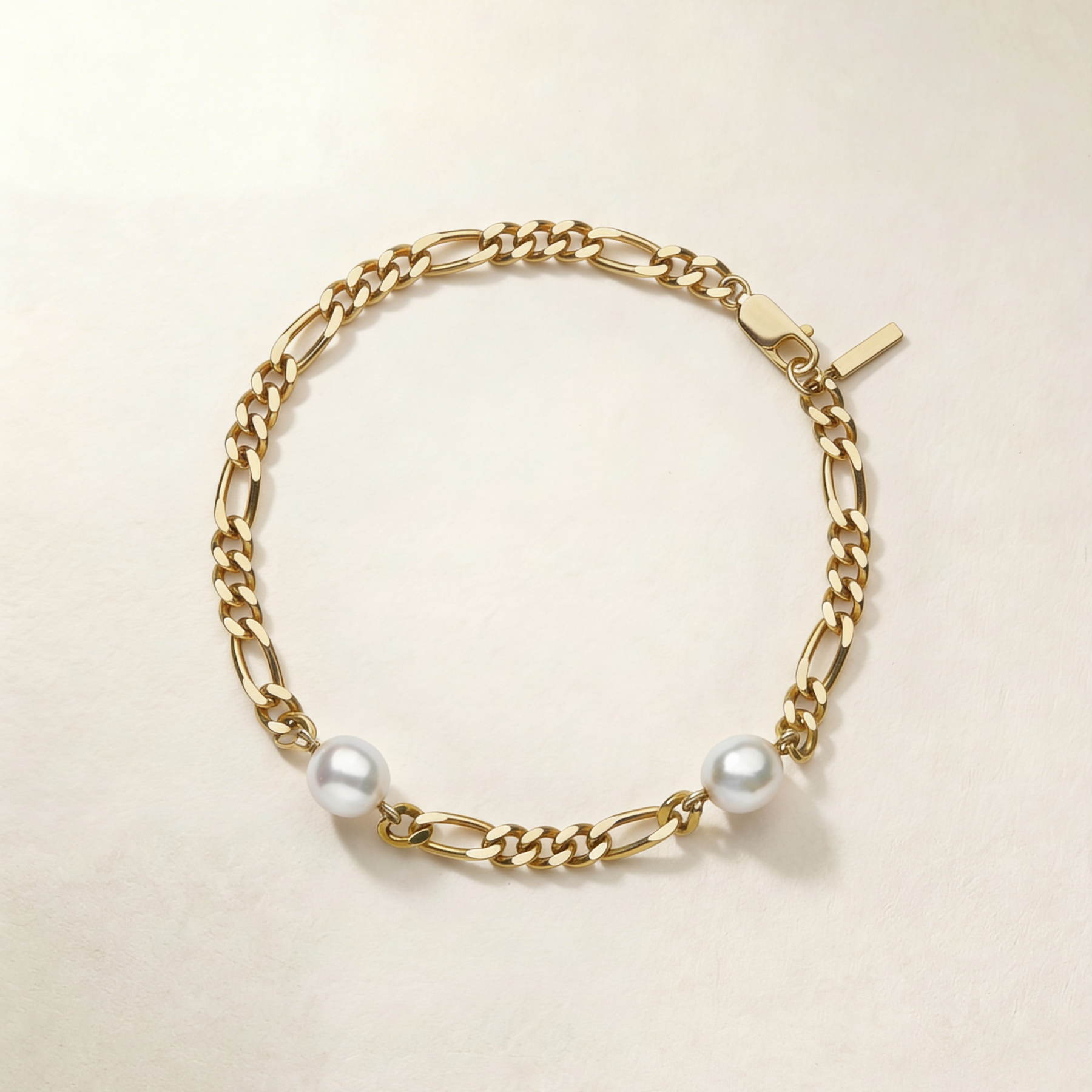 Gold chain anklet with pearls on a beige background