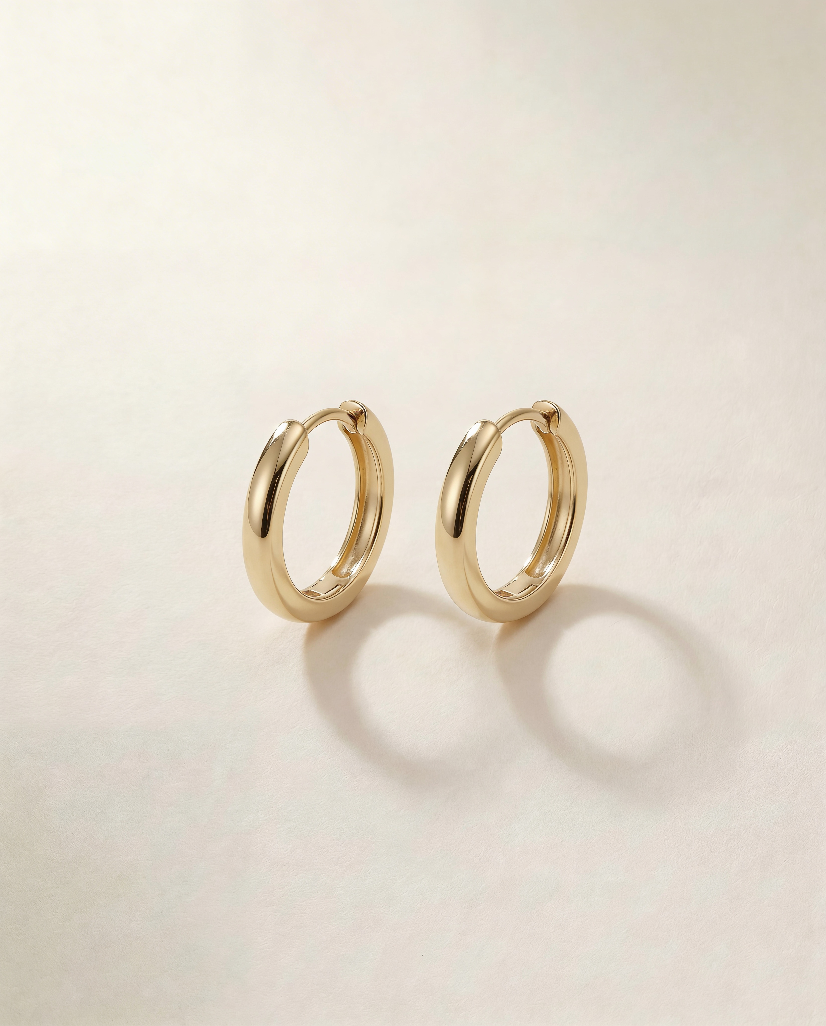 Gold hoop earrings on a light beige background