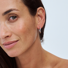 Close-up of a woman wearing a 9k white gold hoop earring against a light background