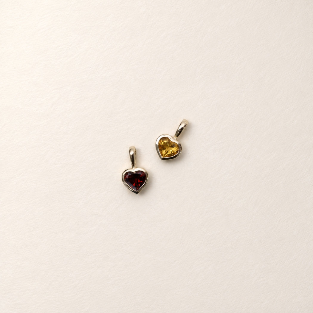 A citrine and garnet heart-shaped pendant charm, bezel set in 9k yellow gold
