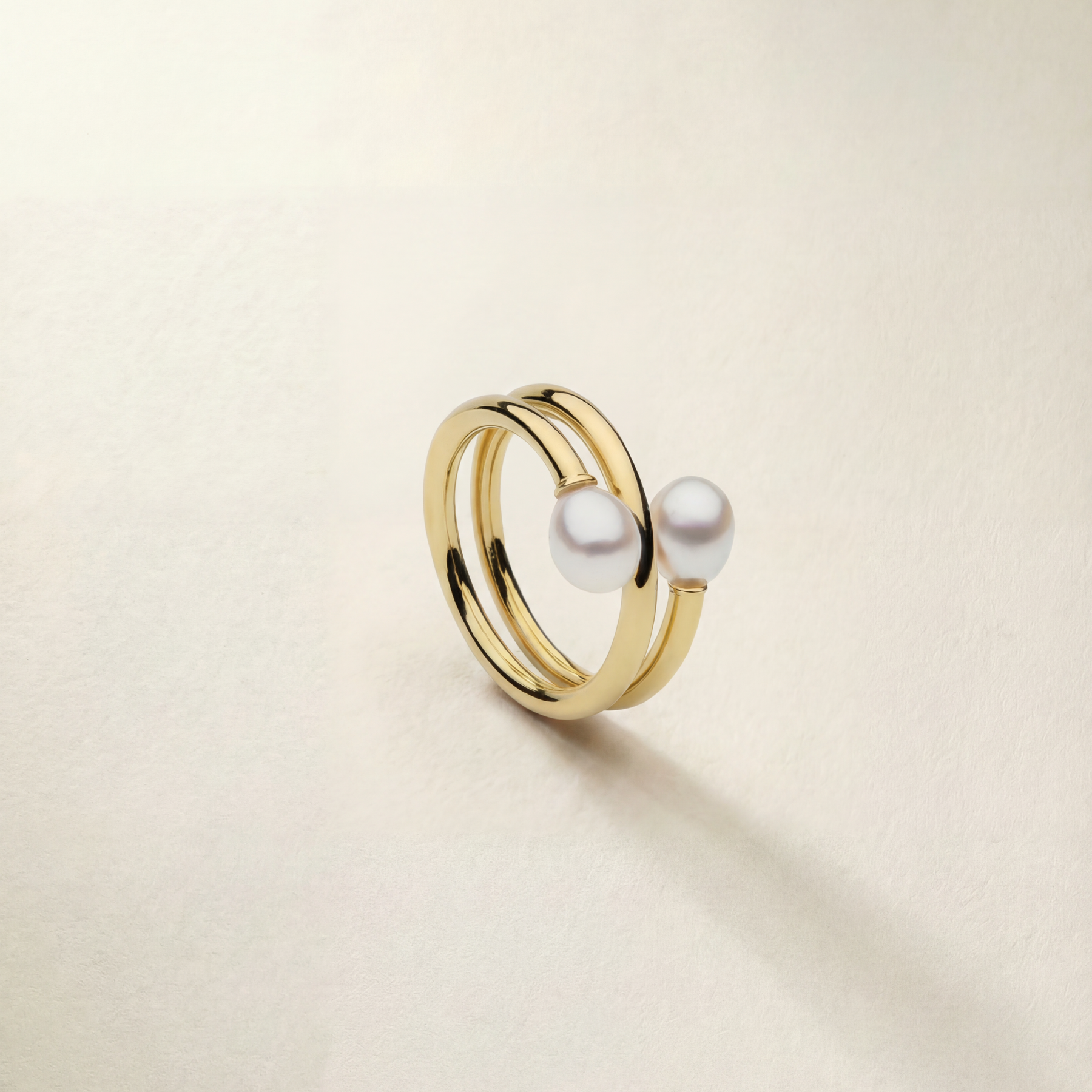 Gold ring with two pearls on a beige background