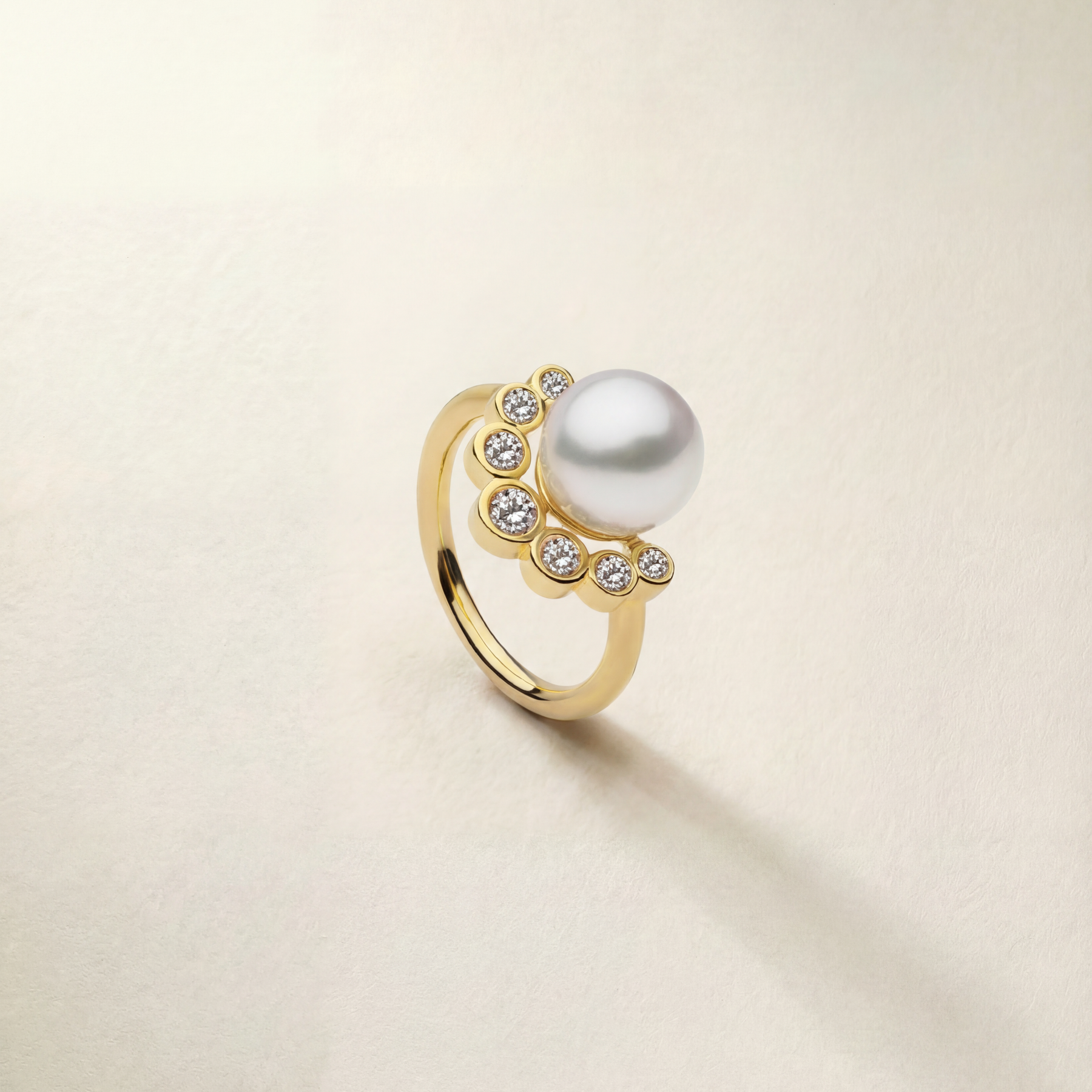 Gold ring with a pearl and small diamonds on a beige background