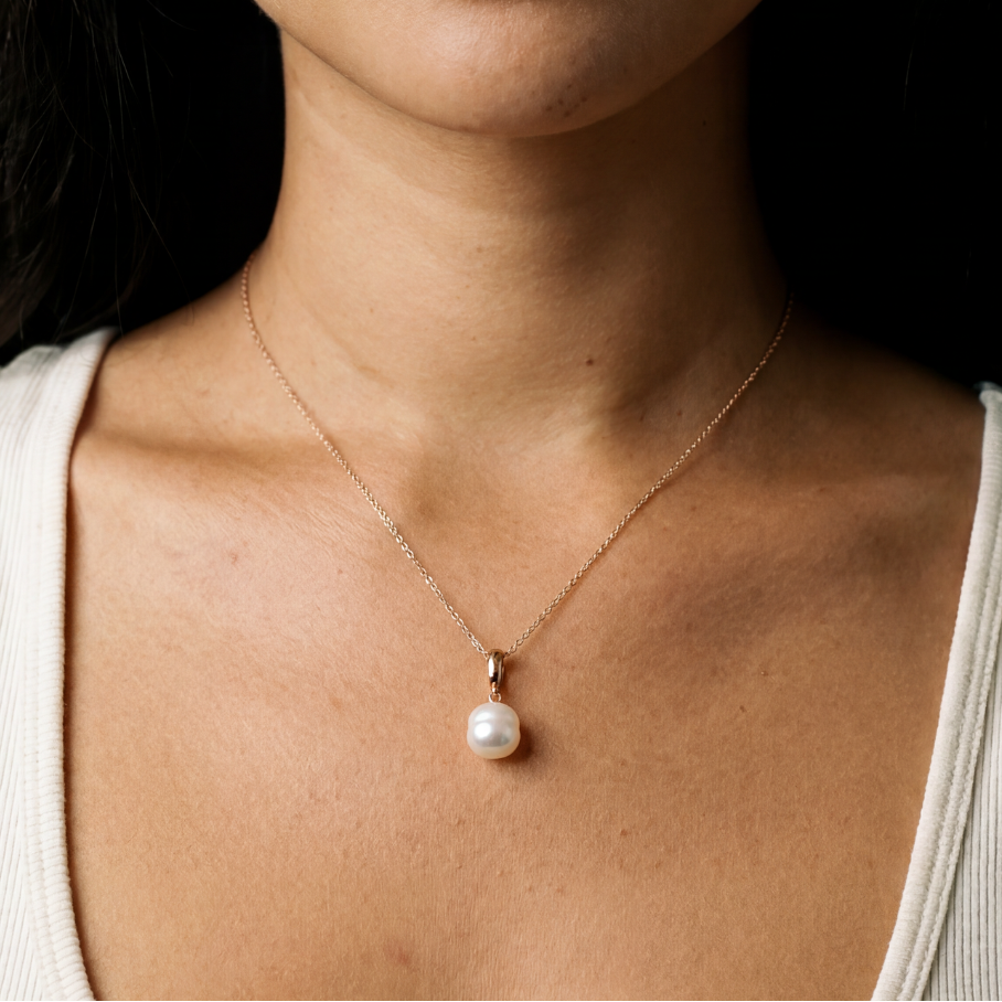 Close-up of a woman wearing a pearl necklace with a neutral background