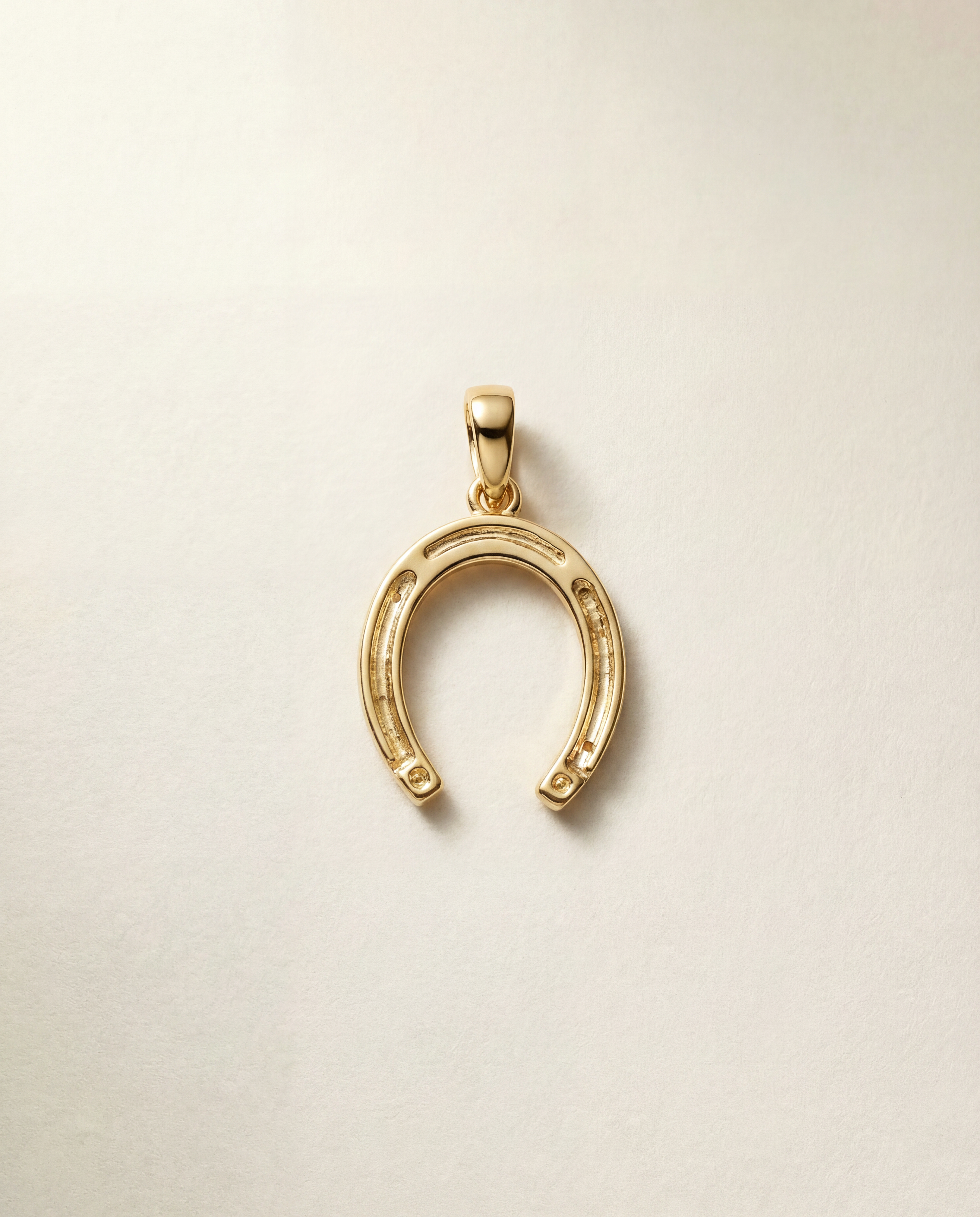 Gold horseshoe pendant on a beige background