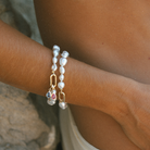 Up close of wrist wearing handmade South Sea Keshi pearl bracelets with 9k solid gold clasp with Blue and Pink Sapphire charms.