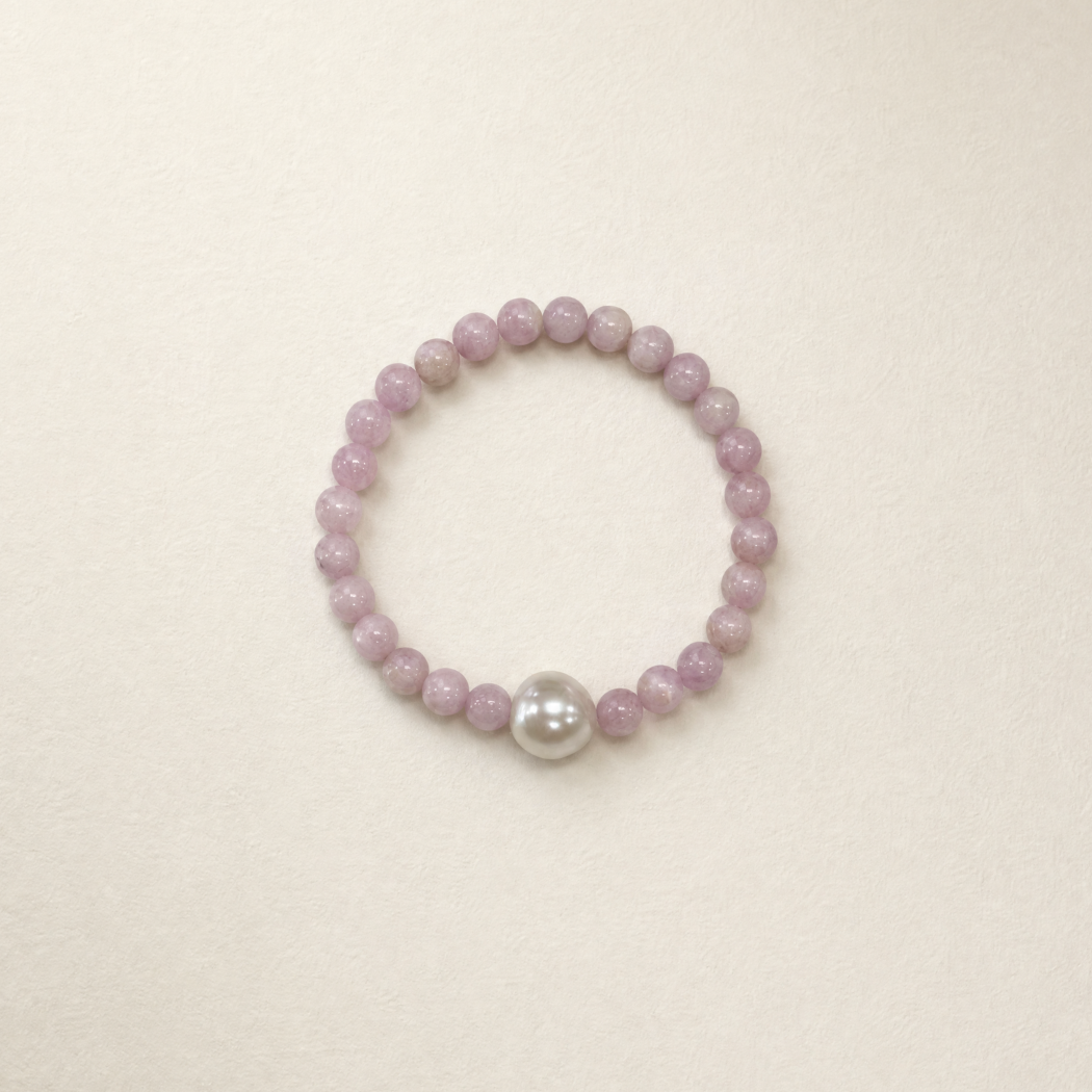 kunzite beaded bracelet with a central pearl on a beige background