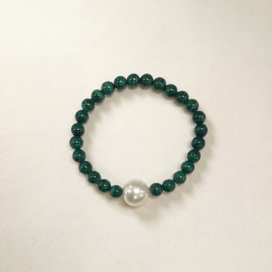 Green beaded bracelet with a white pearl on a beige background