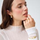 Woman wearing melanie south sea pearl earrings, ring, and bracelet in 18k yellow gold vermeil.