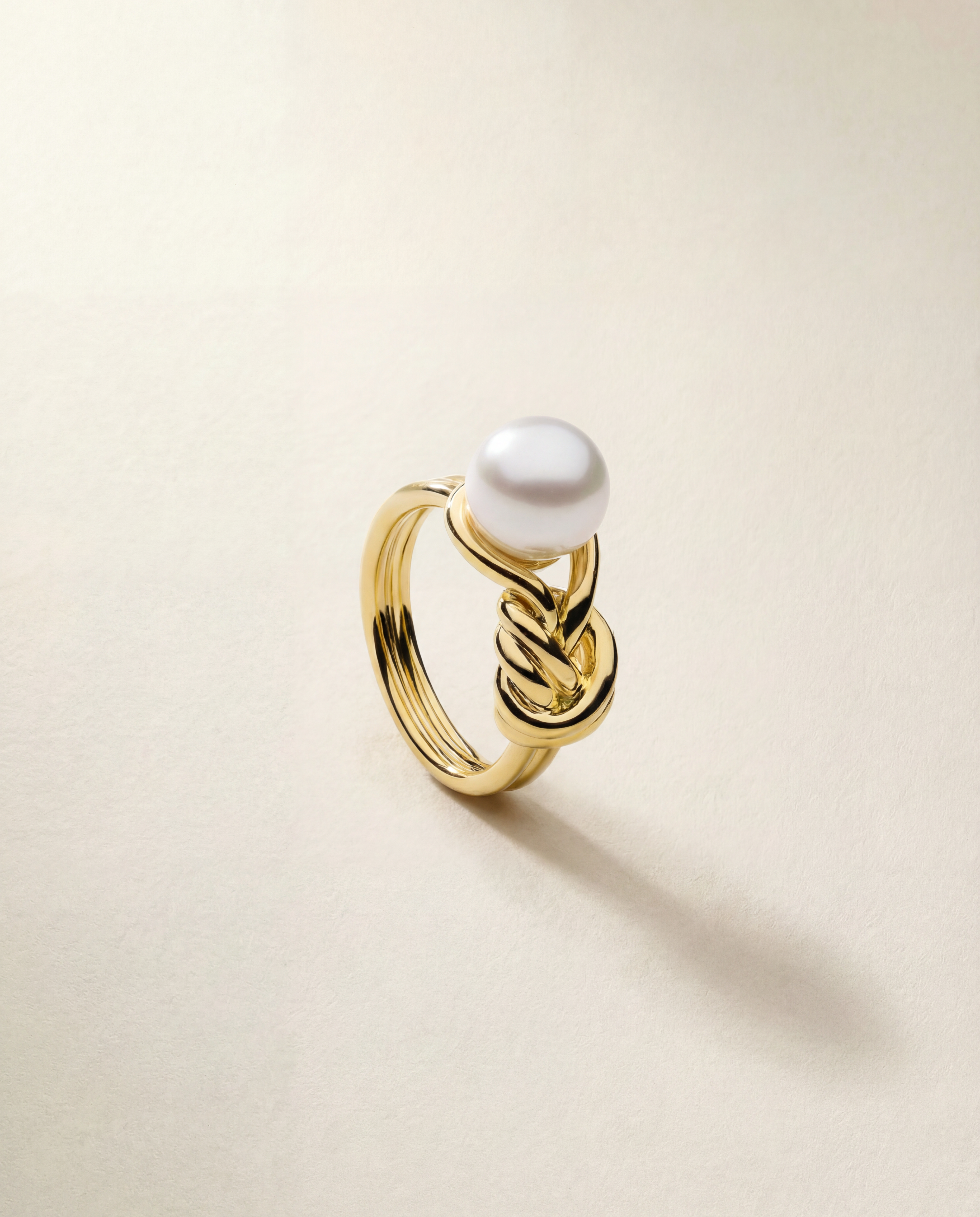 Gold ring with a pearl on a beige background