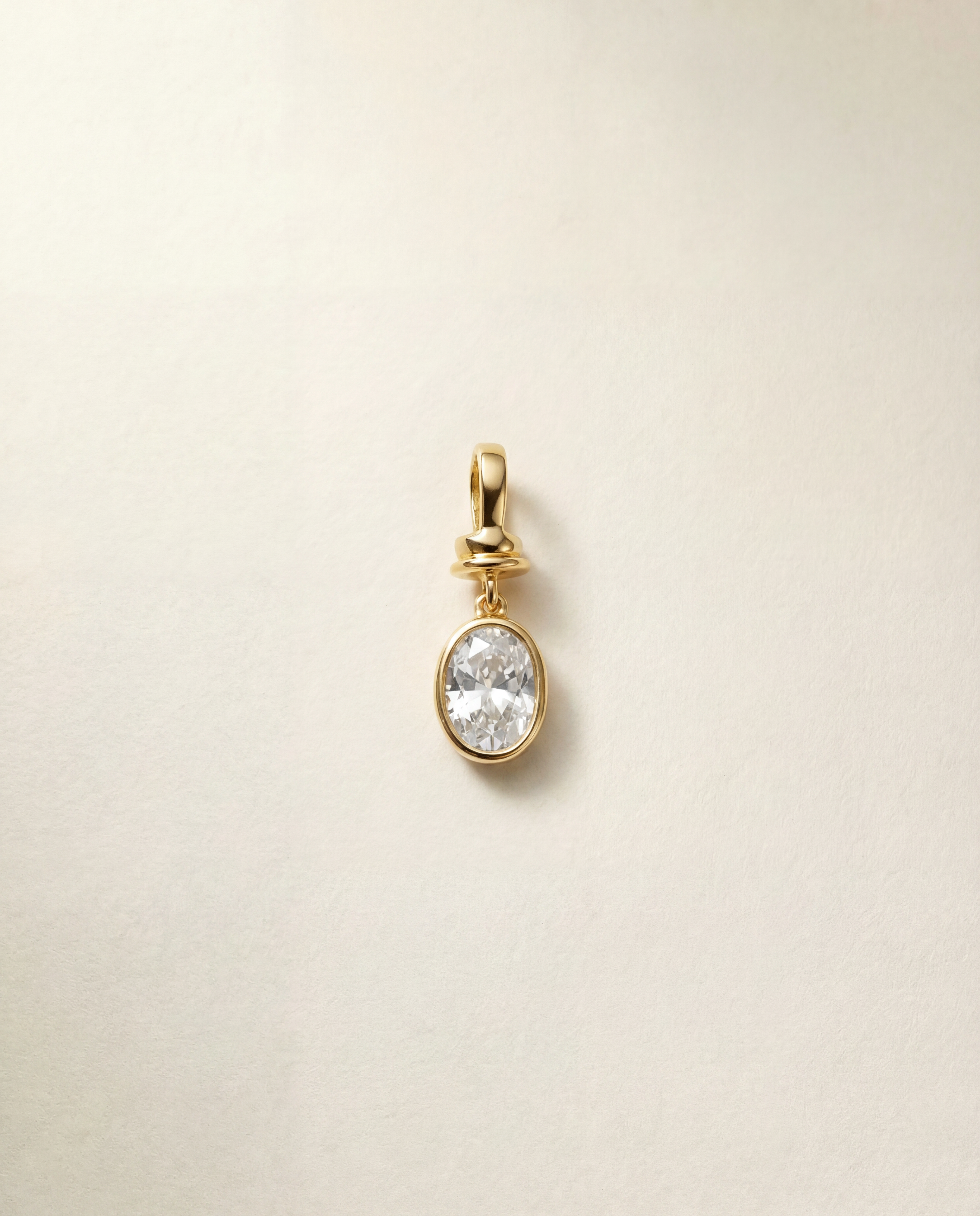 Gold pendant with a diamond gemstone on a beige background
