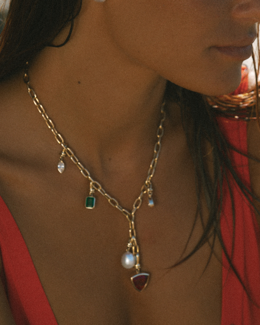 Close-up of 9k solid gold Italian chain necklace with various gemstones and pearl charms.