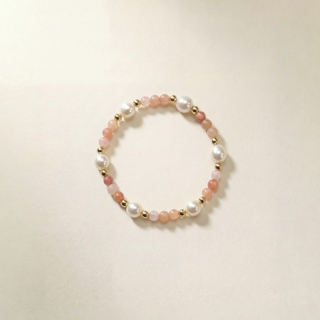 Beaded bracelet with pearls and gold accents on a beige background